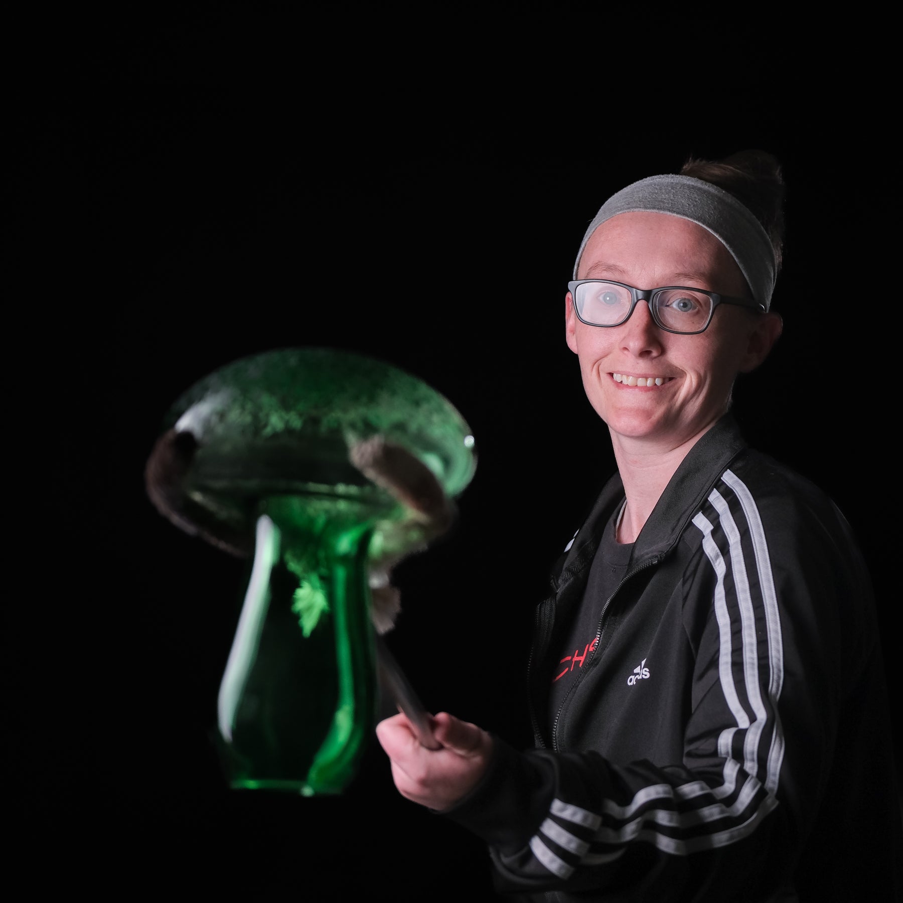 Person holding a green glass object against a black background