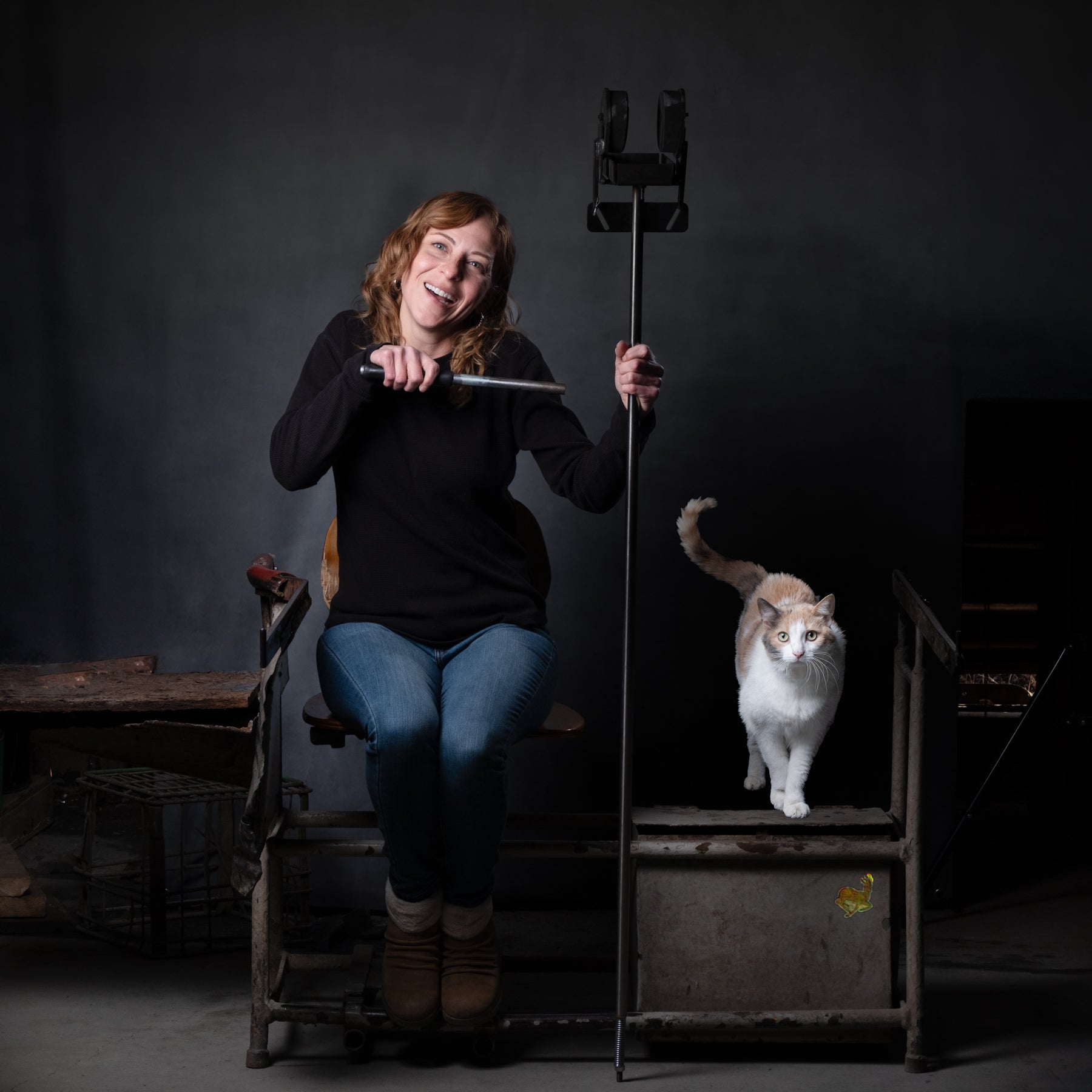 Lisa with glassblowing tool and a cat beside her.