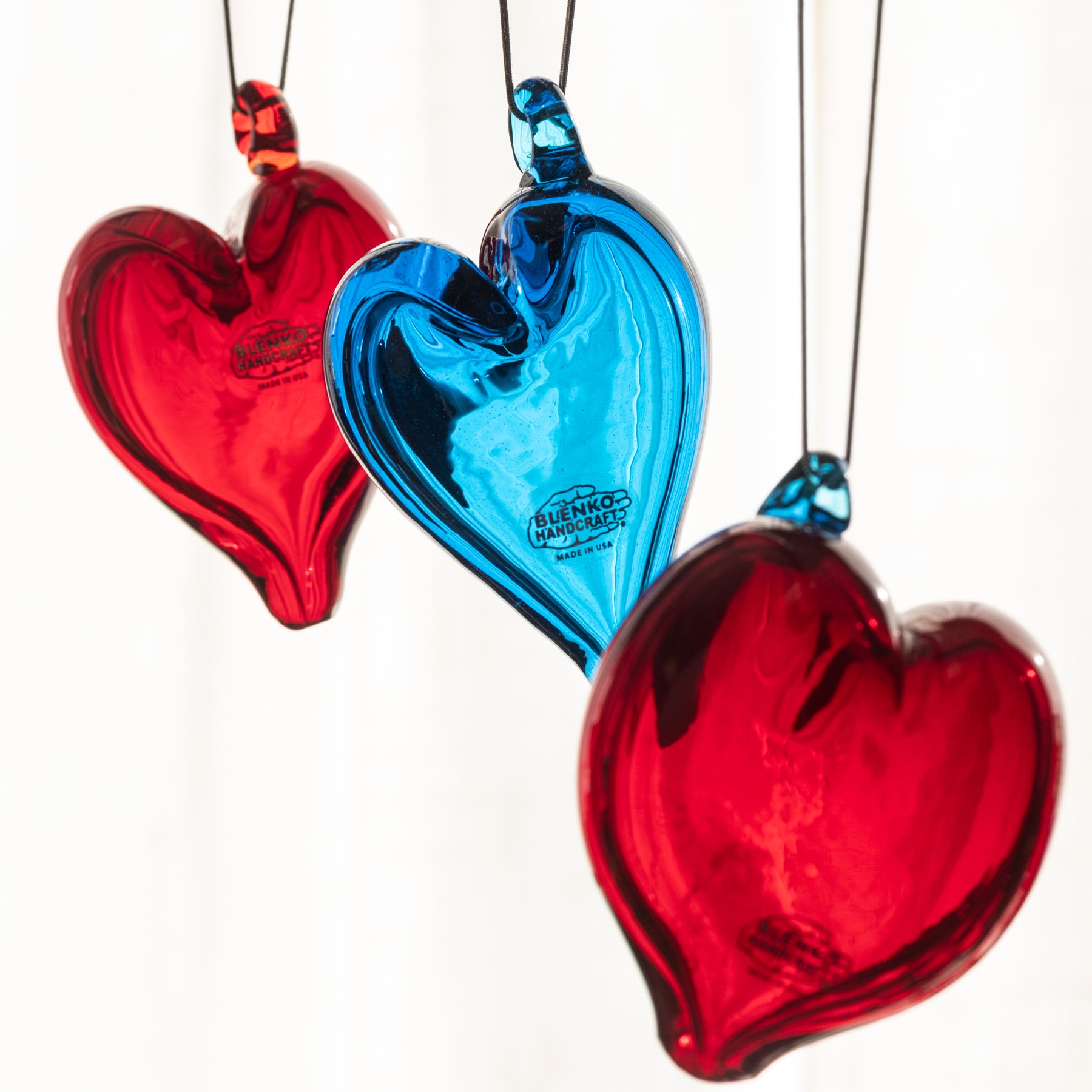 Three heart-shaped glass ornaments in red and blue on a white background