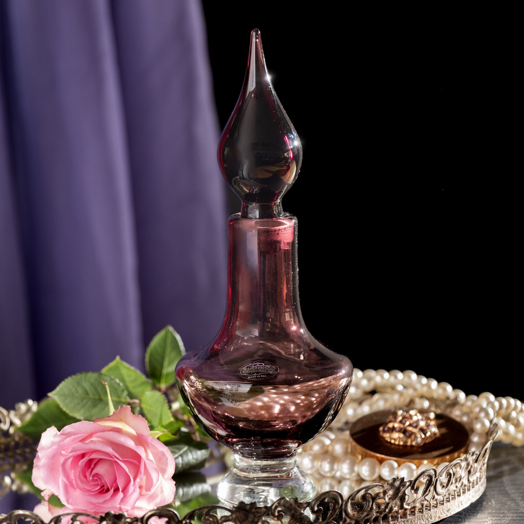 Amethyst decanter with pink rose flower on a tray