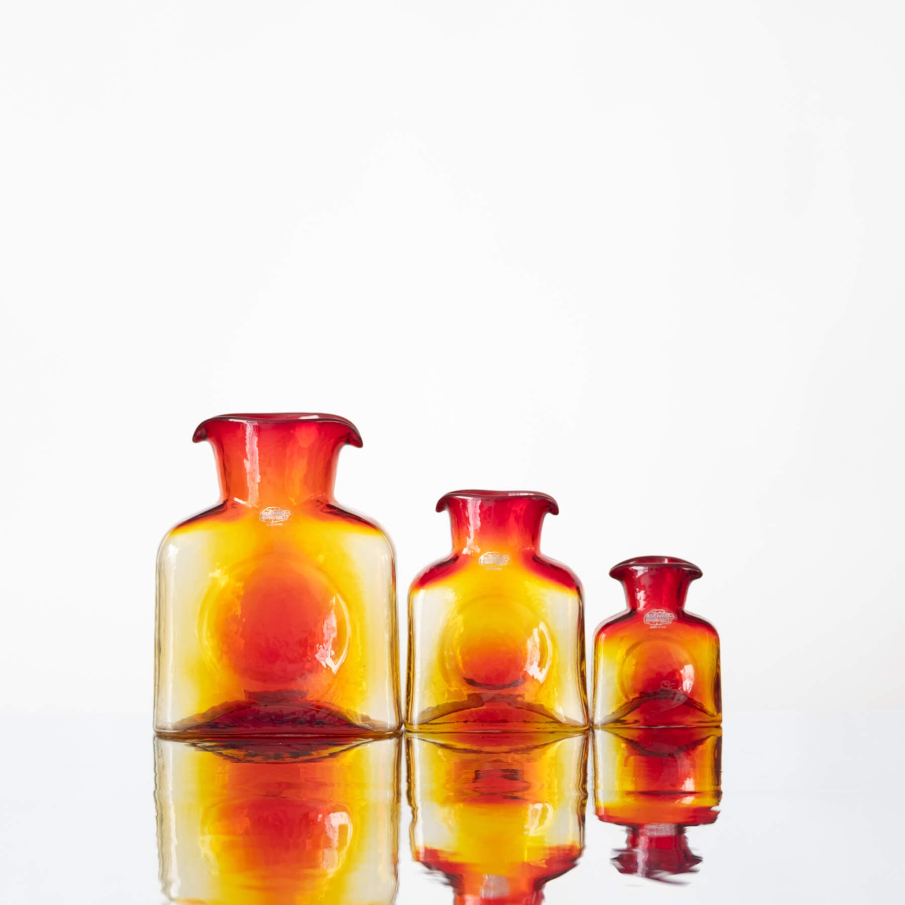 Three glass bottles with a gradient color from red to yellow on a white background