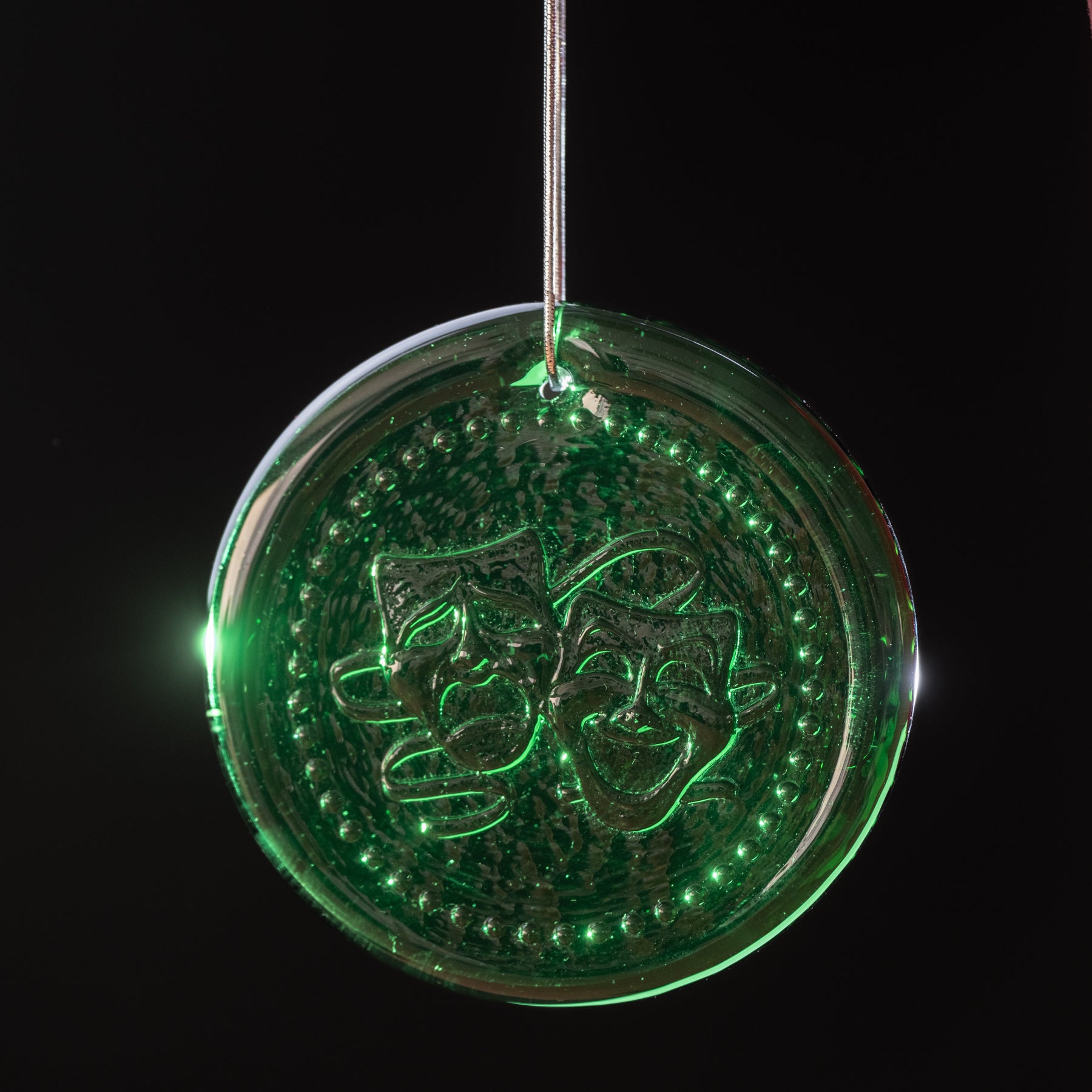 Circular green ornament with decorative design on a black background