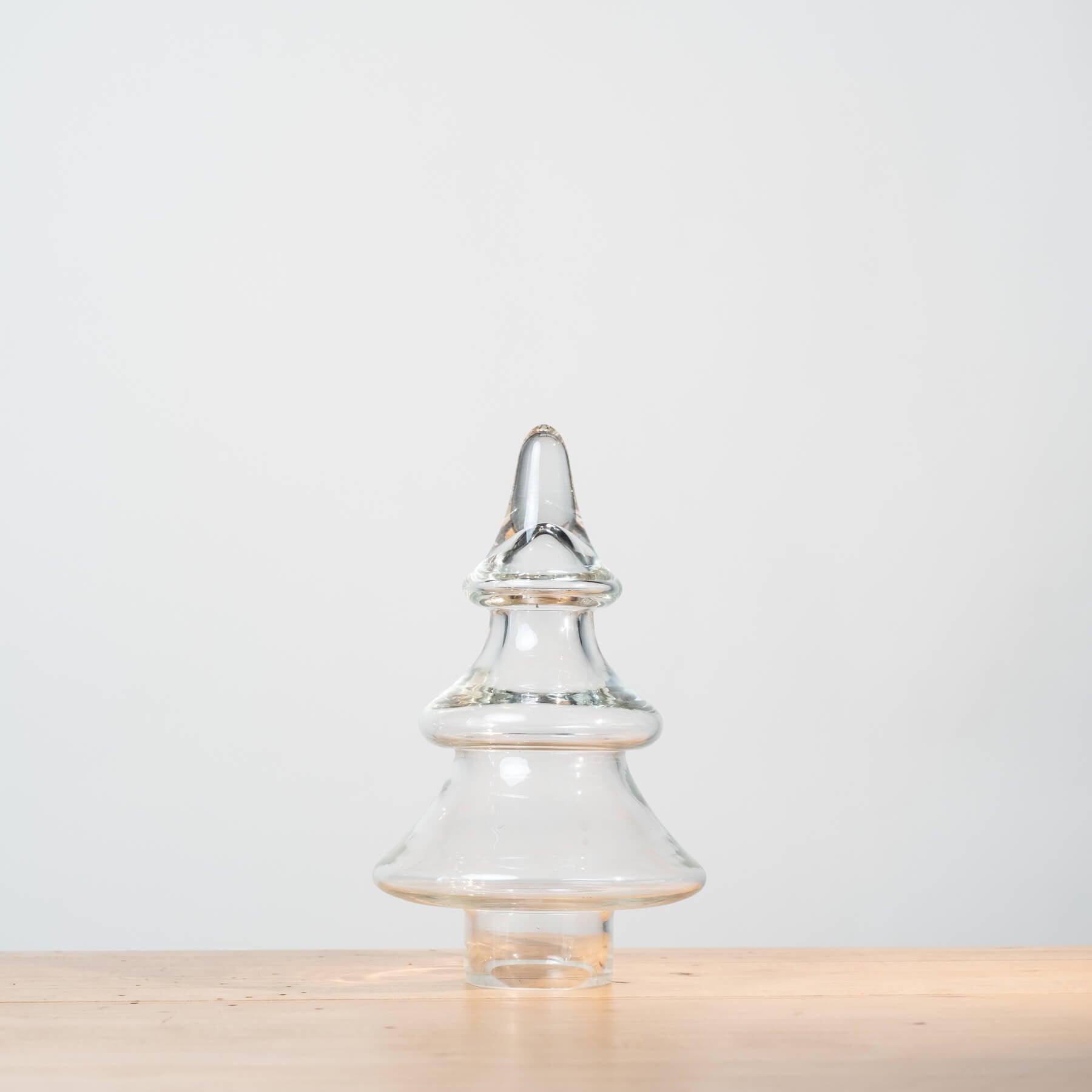 Clear glass Christmas tree ornament on a light wooden surface with a white background