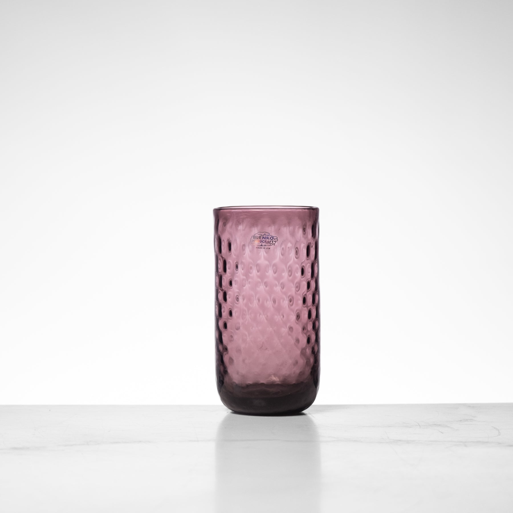 Pink glass tumbler with textured surface on a white background