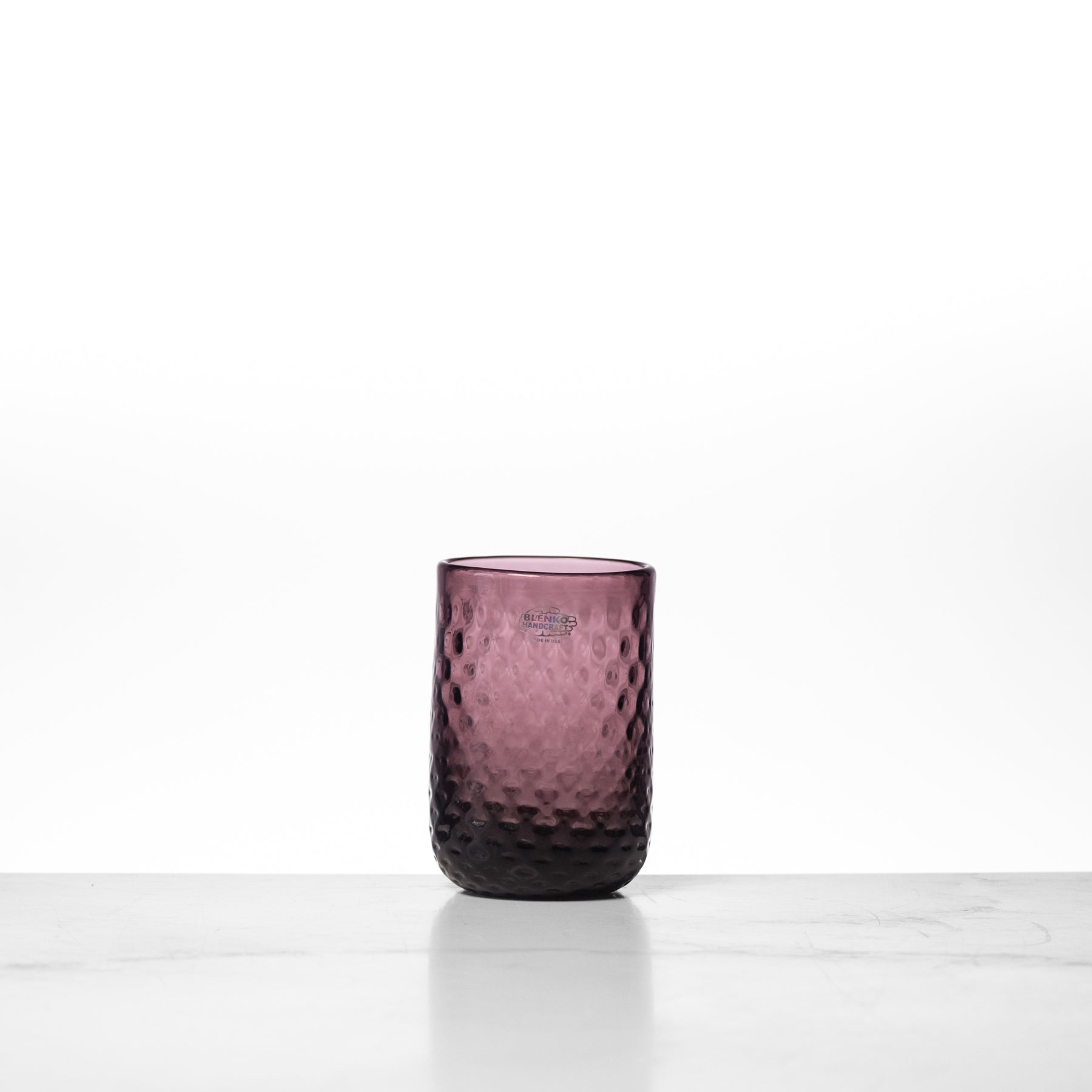 Purple textured glass tumbler on a white background