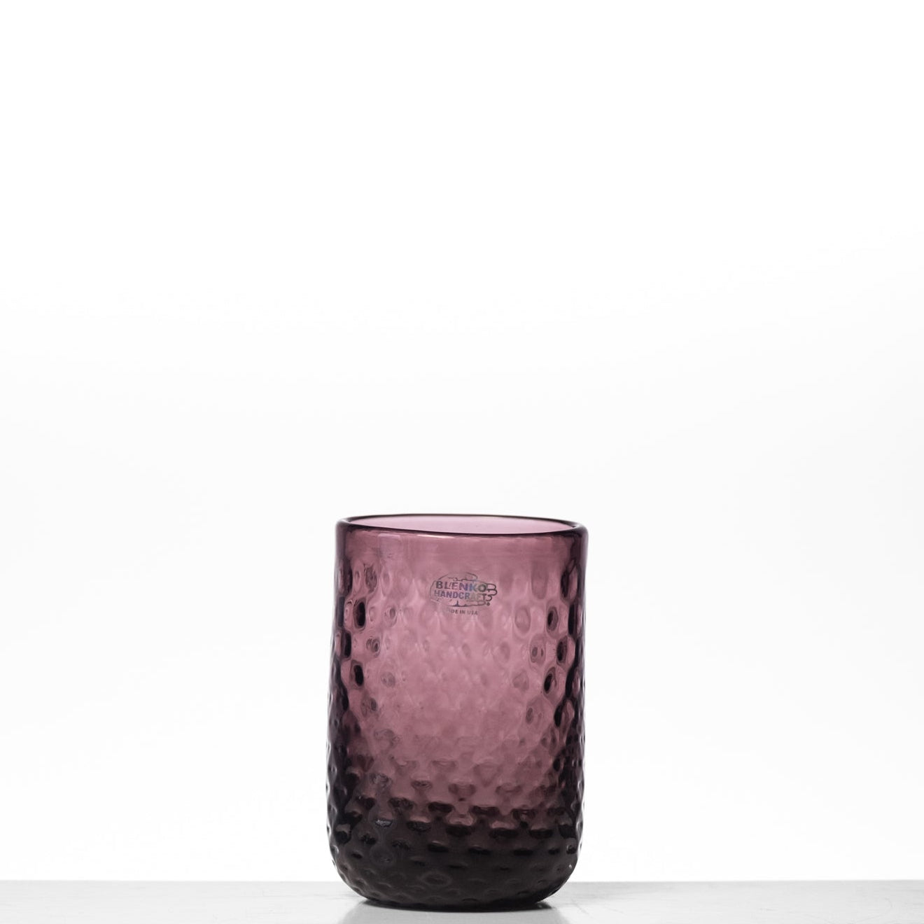 Purple textured glass tumbler on a white background