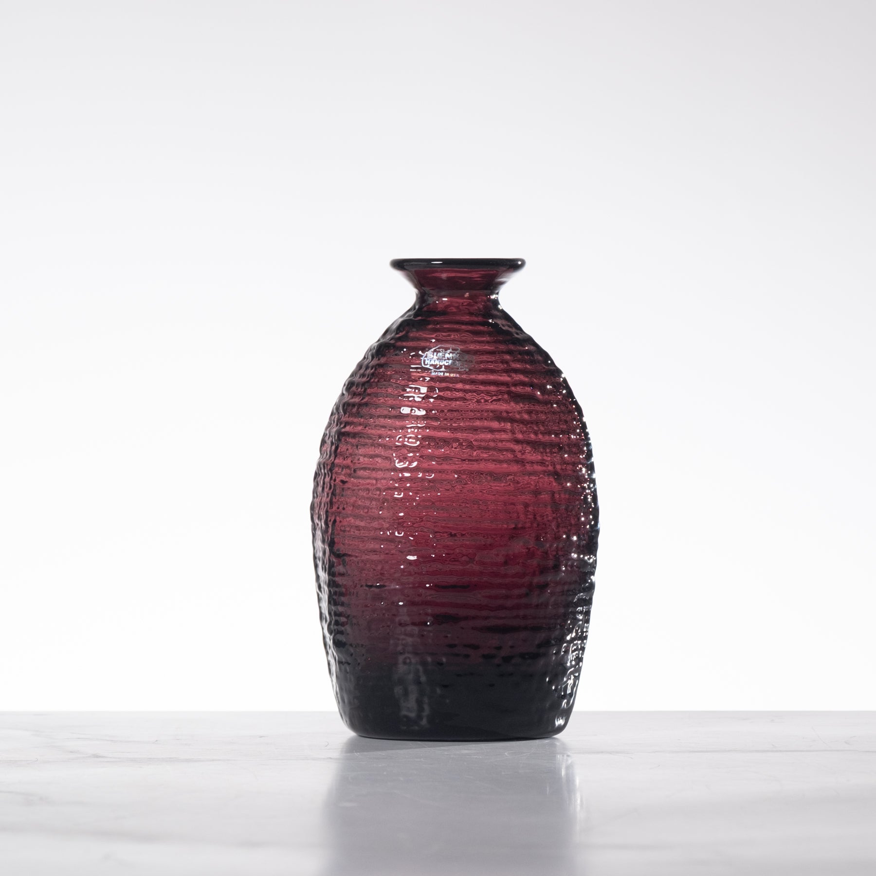 Red glass vase with textured surface on a white background