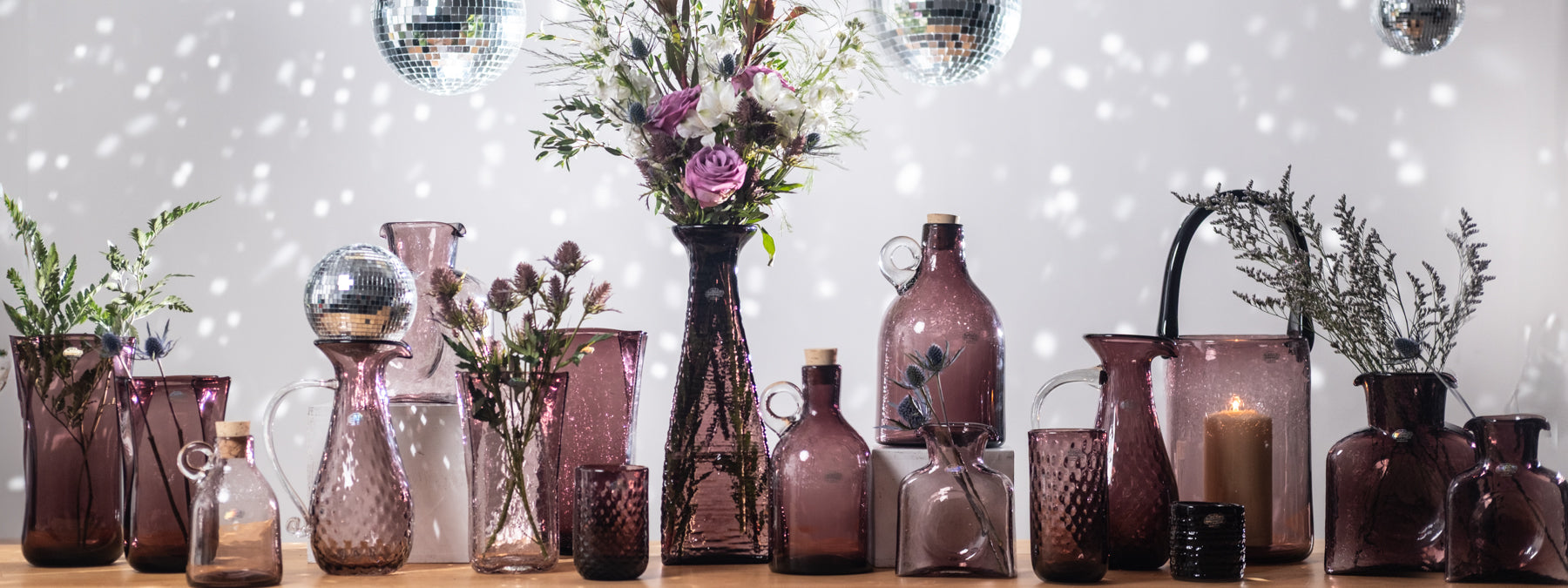 Collection of decorative vases and bottles on a wooden surface with a festive background.