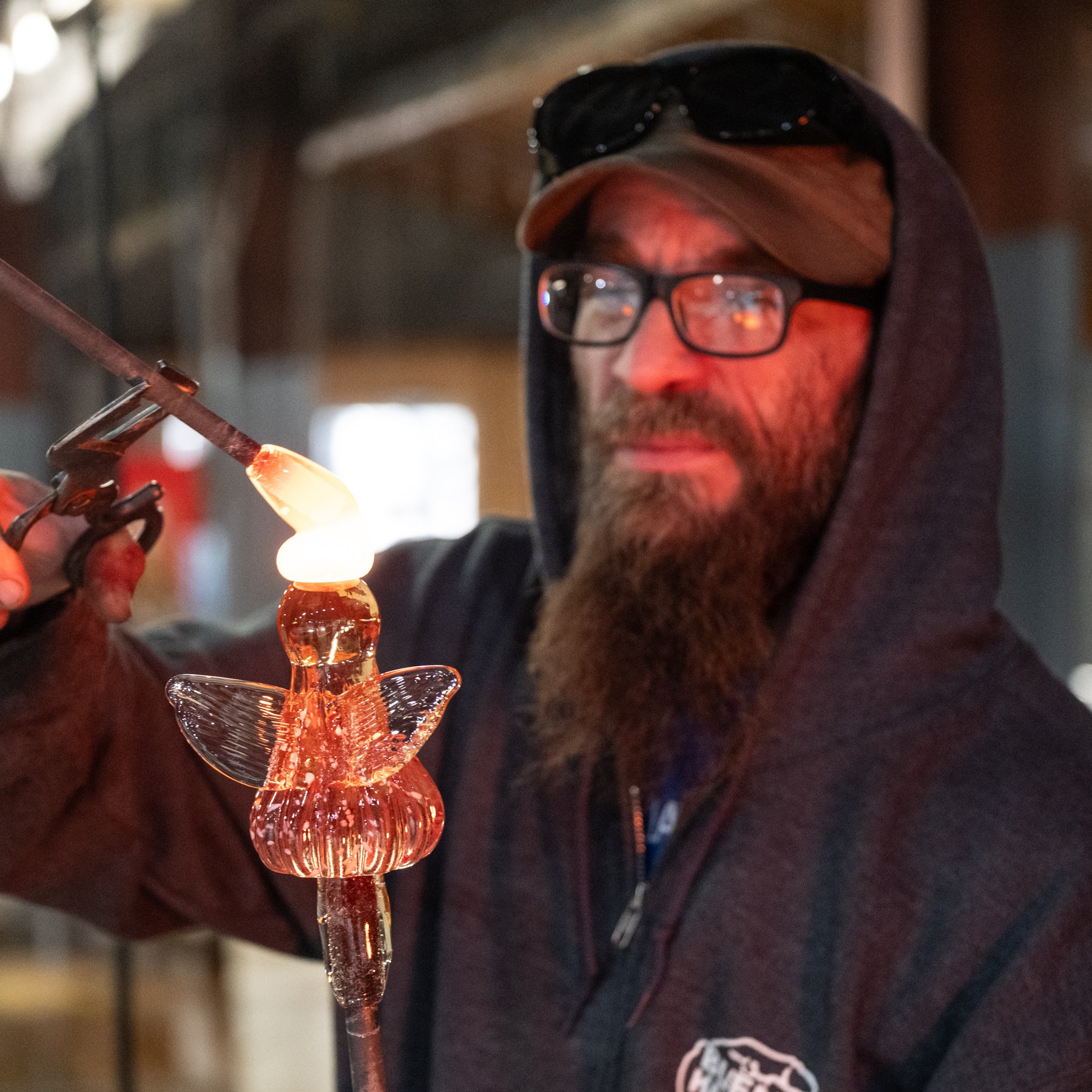 Person working with molten glass shaped like a butterfly
