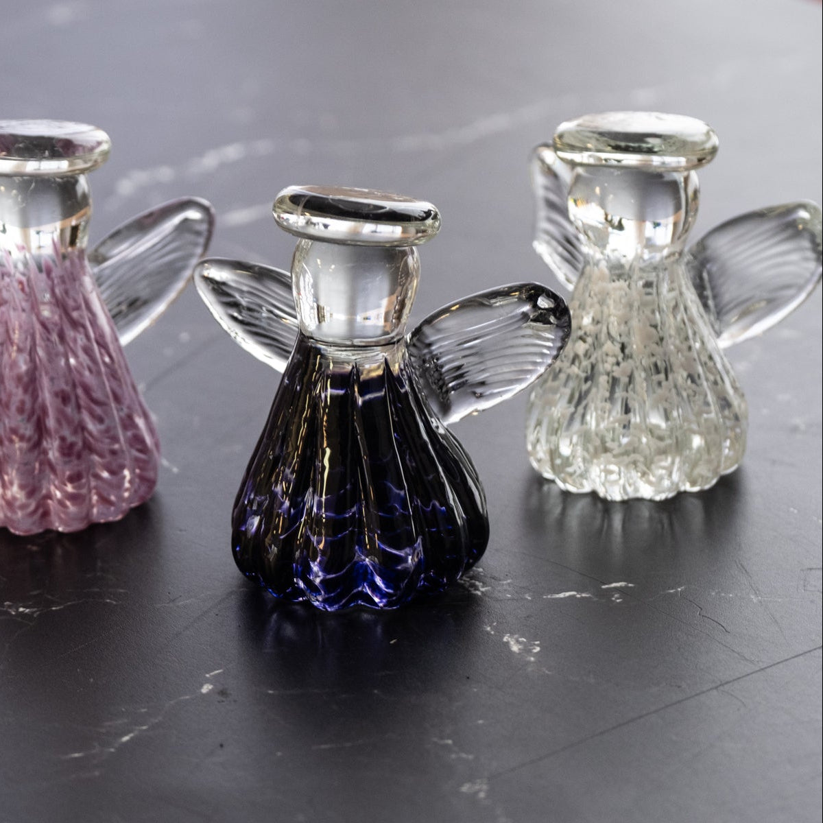 Set of five glass angel figurines on a dark surface