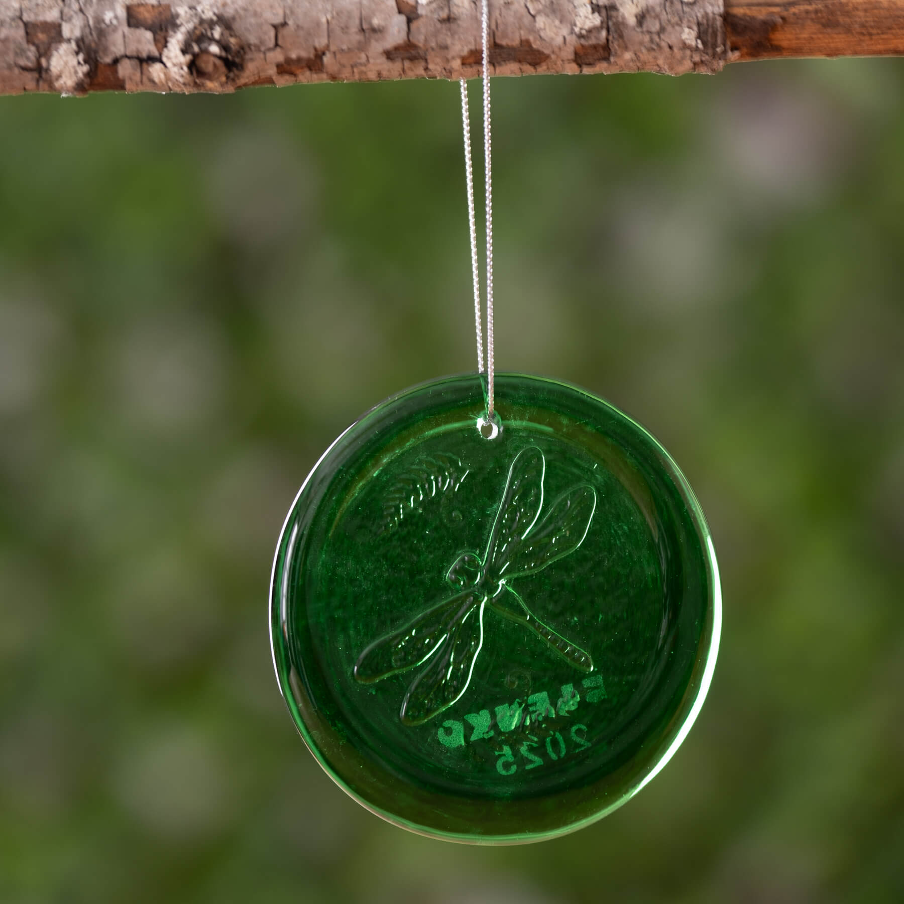 A 3-inch round green suncatcher with a dragonfly design hanging from a string.