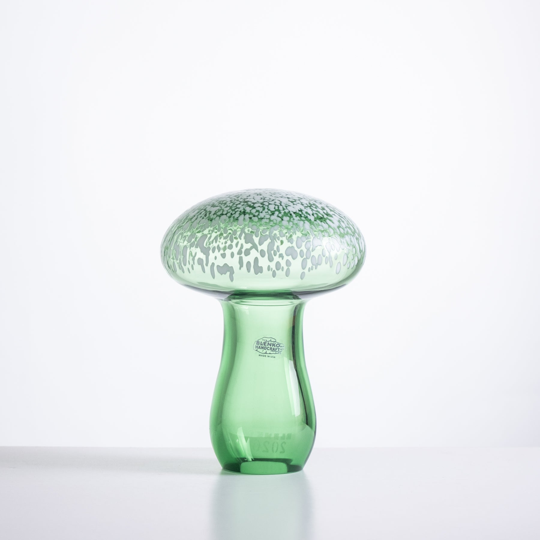 Green glass mushroom-shaped object on a white background