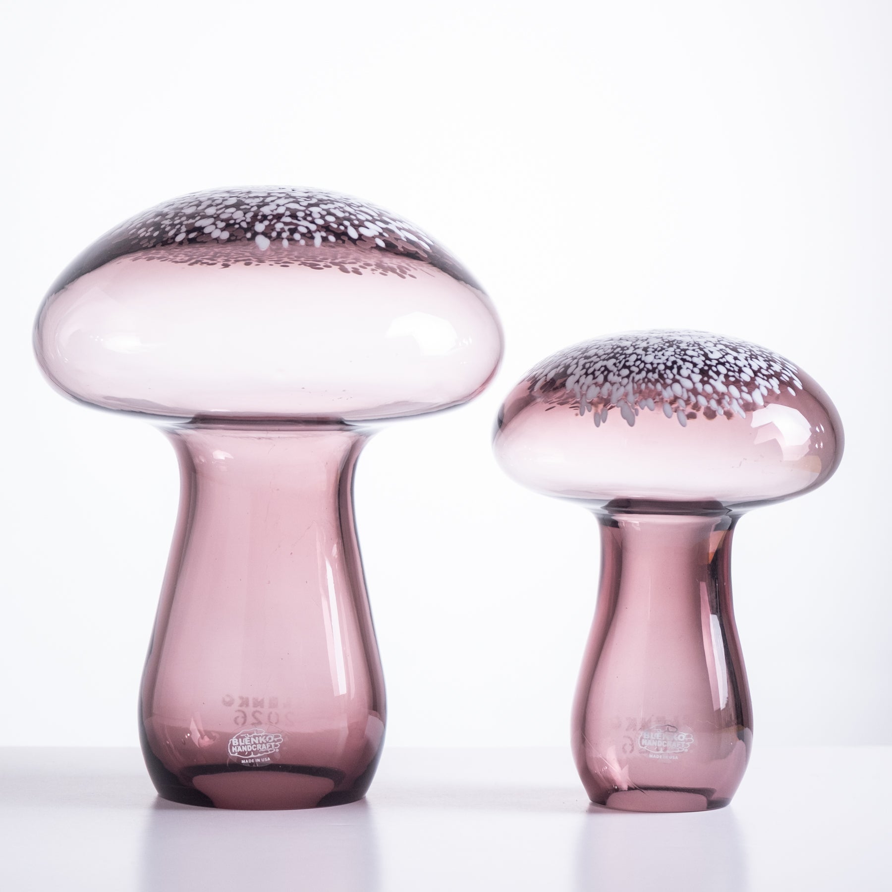 Two pink glass mushroom-shaped objects on a white background