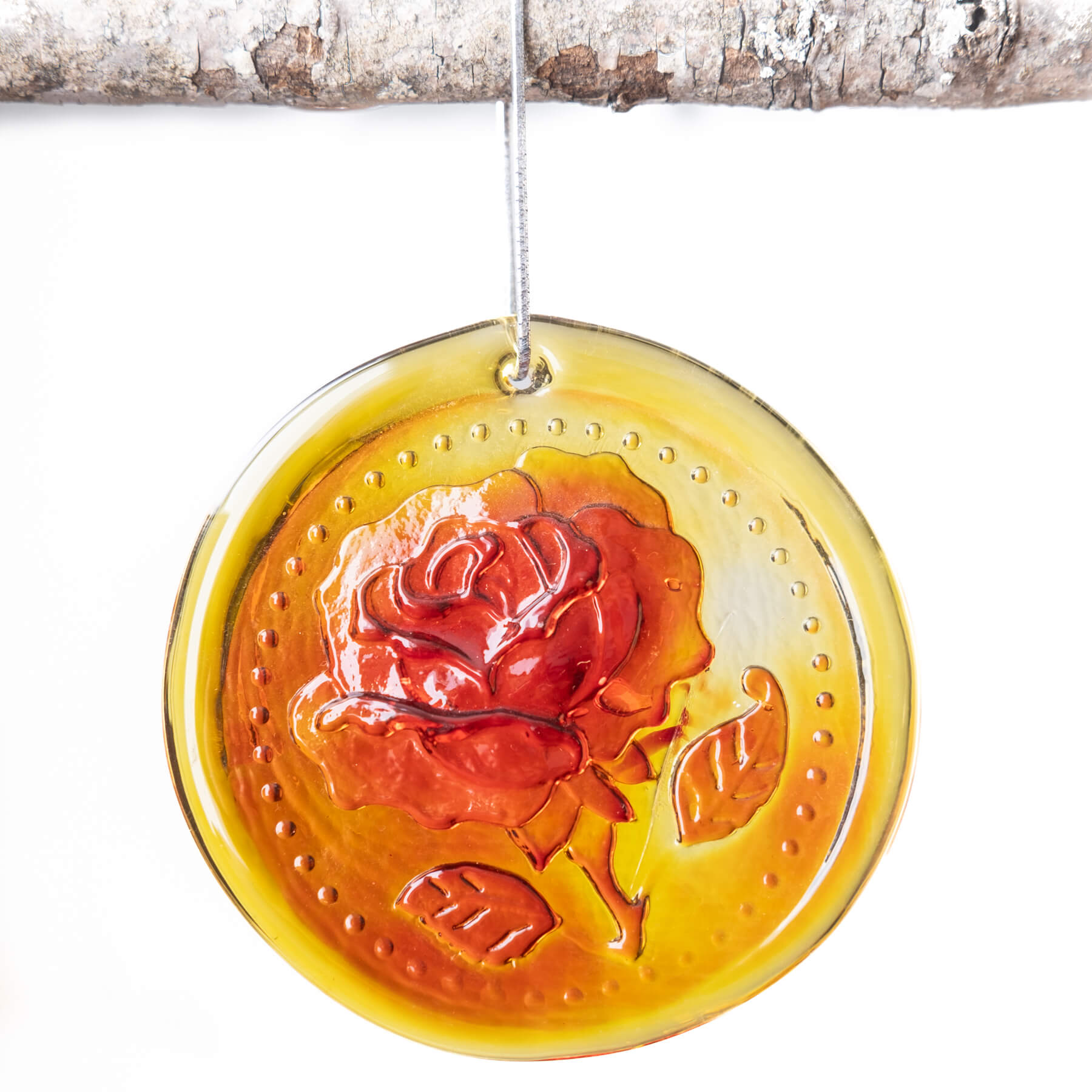 A handcrafted glass suncatcher with a rose design, in orange and yellow hues, hanging by a string