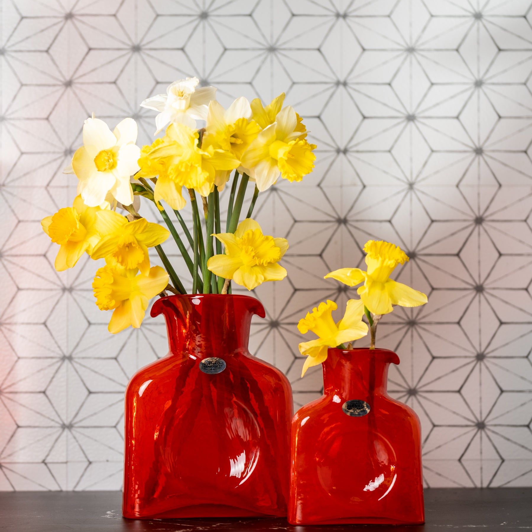 Orange bottles with yellow flowers in front of geometric wallpaper