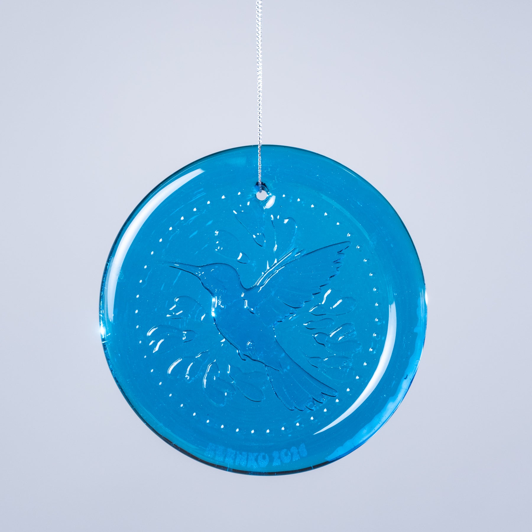 Blue circular ornament with bird design on a light gray background