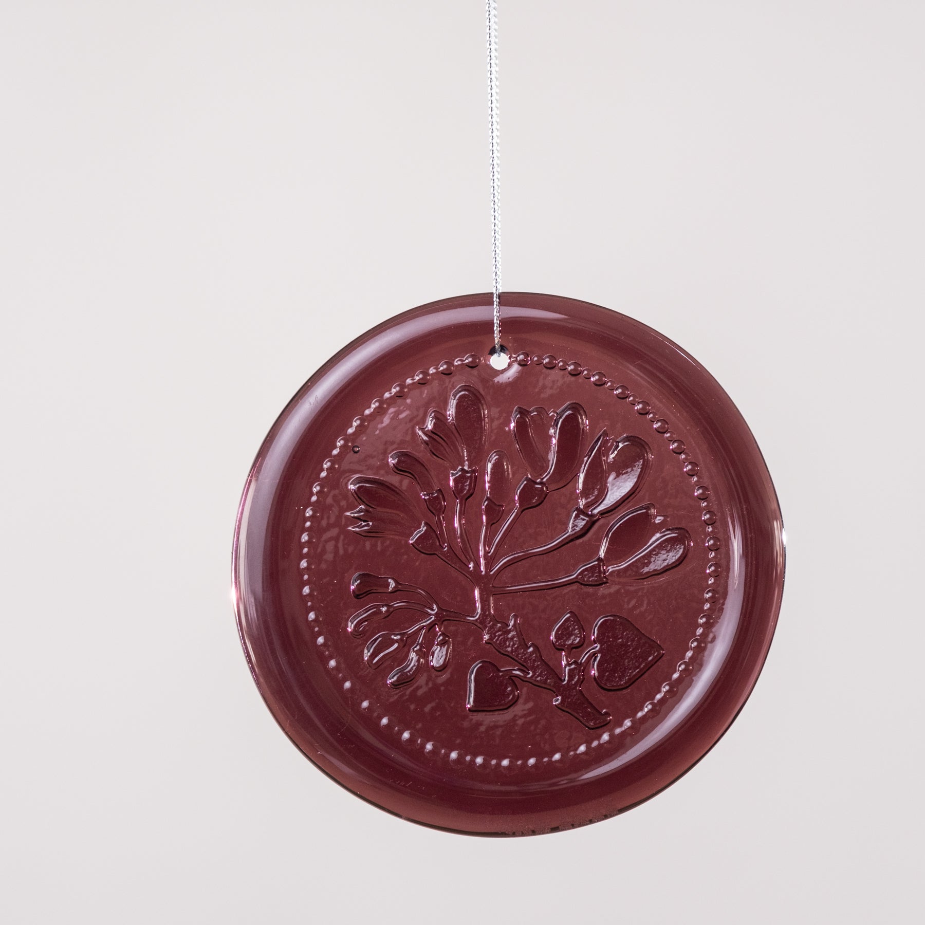 Round brown decorative item with embossed design on a light gray background