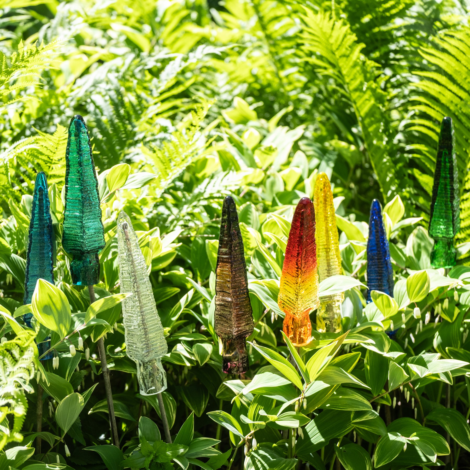 Colorful glass sculptures among green foliage