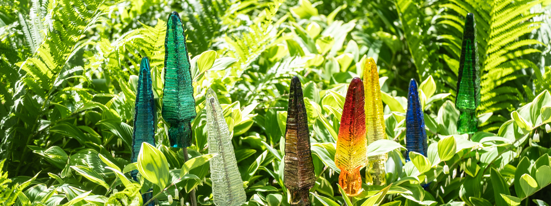 Colorful glass sculptures resembling flowers on a green leafy background