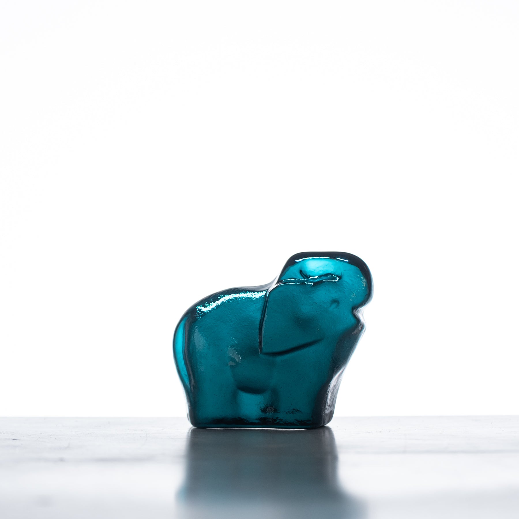 A handcrafted blue glass elephant figurine with a flat back, displayed against a neutral background.