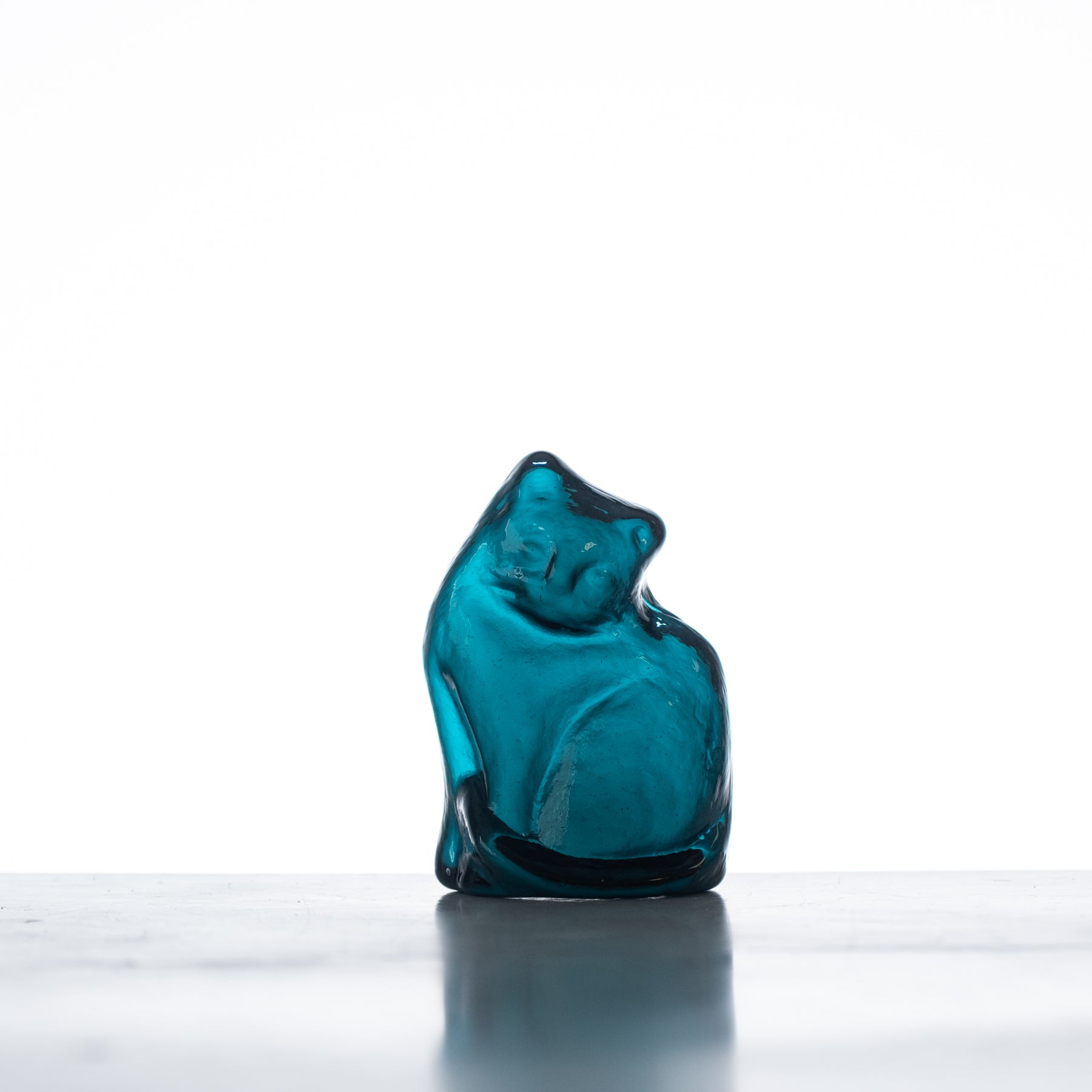 A handcrafted blue glass figurine of a cat with a flat back, displayed against a white background.