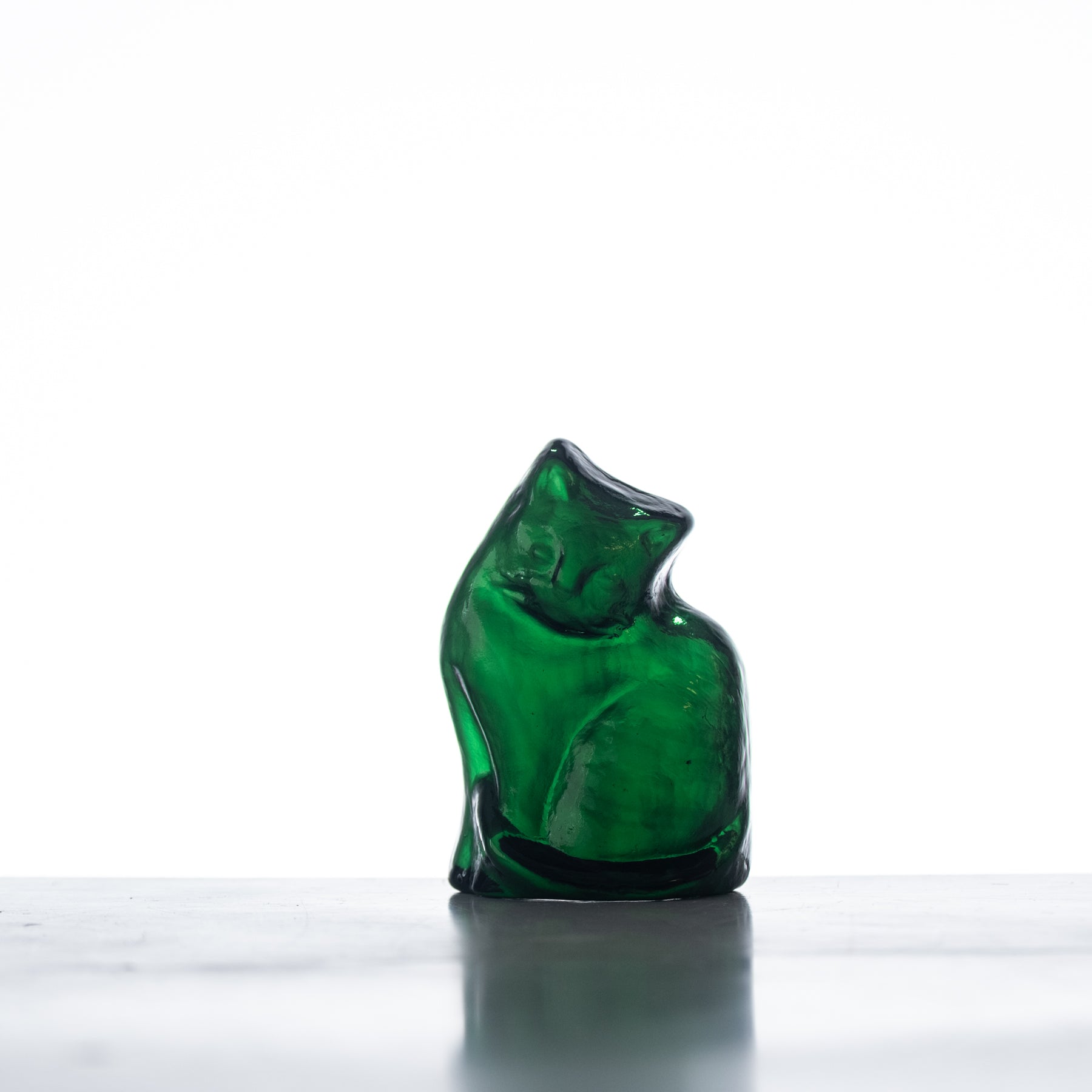 A handcrafted green glass cat figurine with a flat back, displayed against a white background.