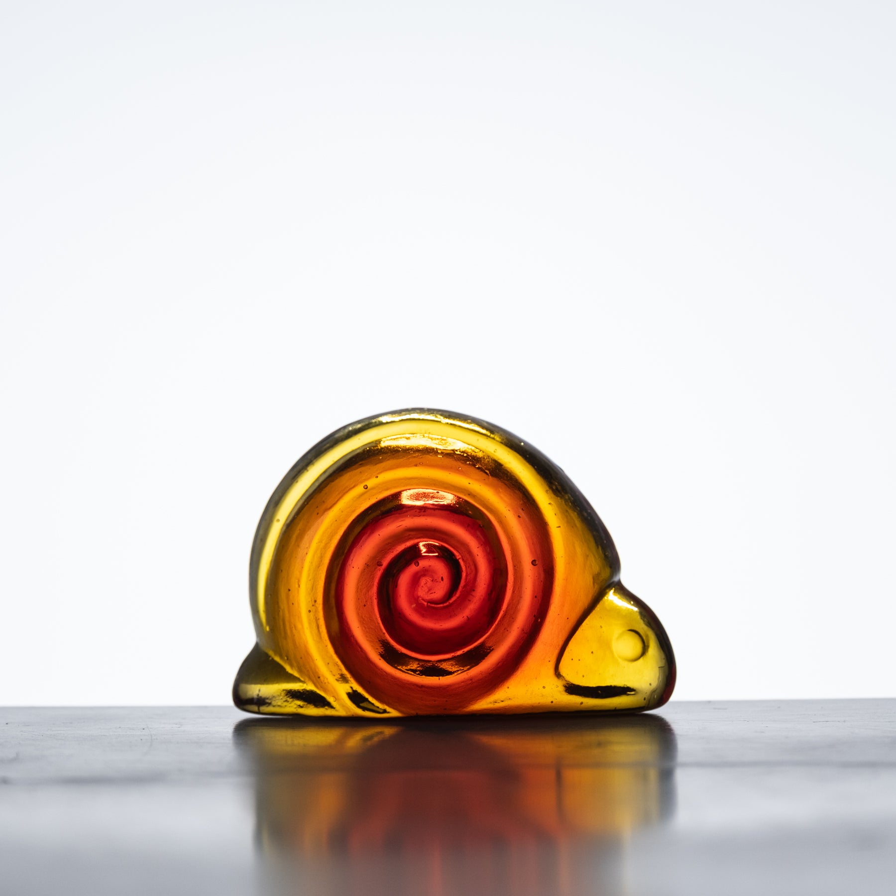 A handcrafted glass snail figurine with a tangerine orange color pattern.
