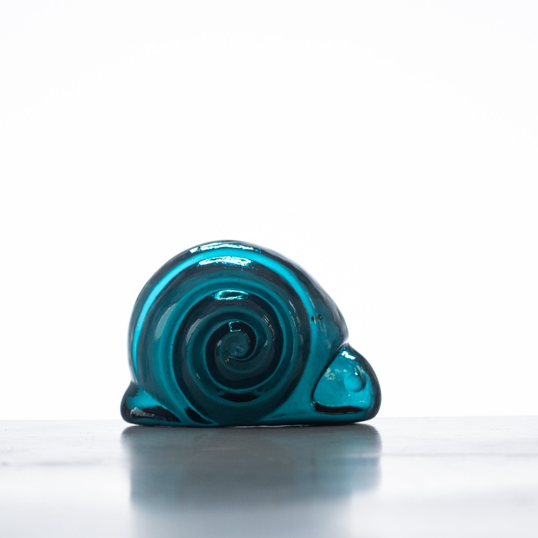 A handcrafted blue glass snail figurine on a flat surface with a white background.