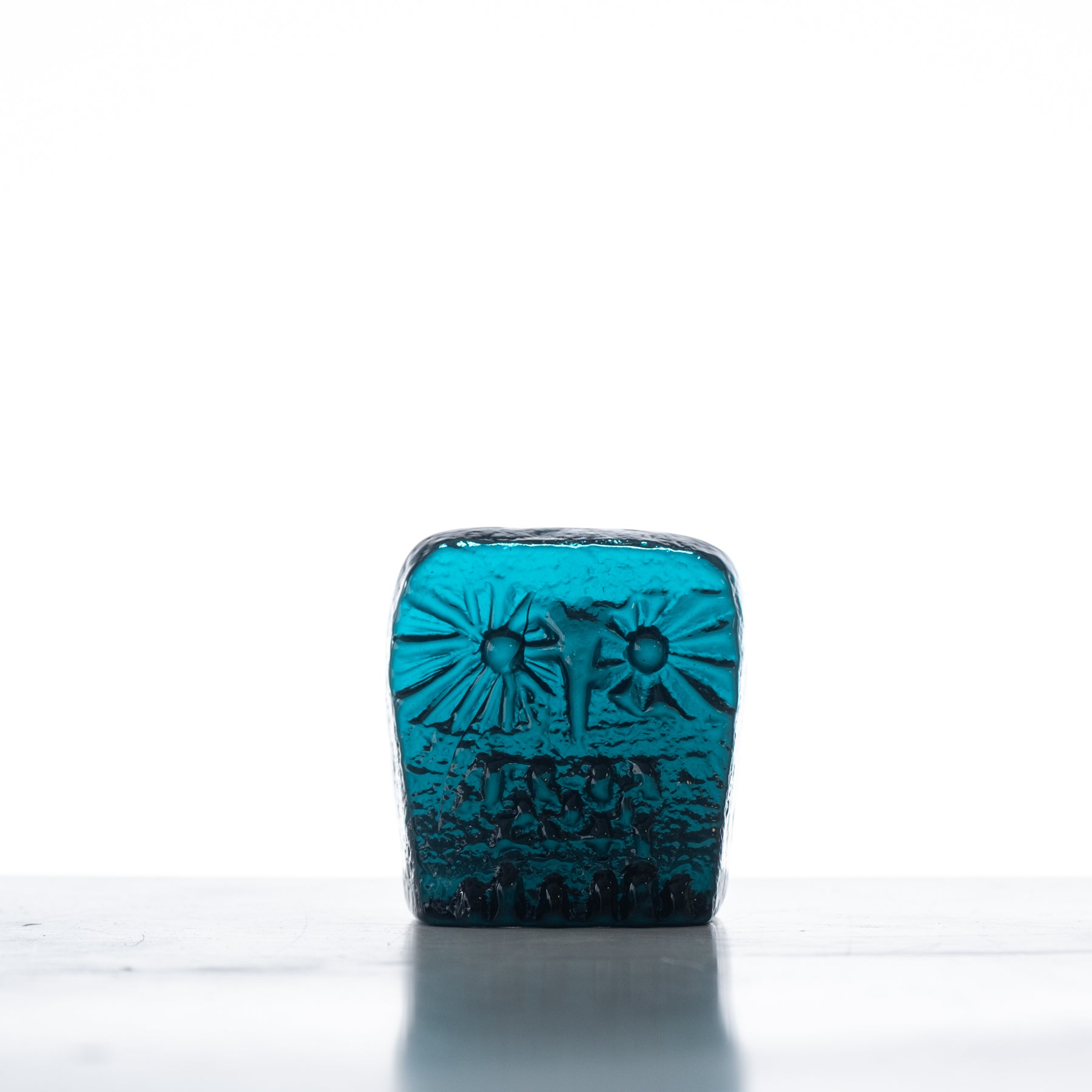 A handcrafted blue glass figurine of an owl on a flat back, with visible patterns and textured details.