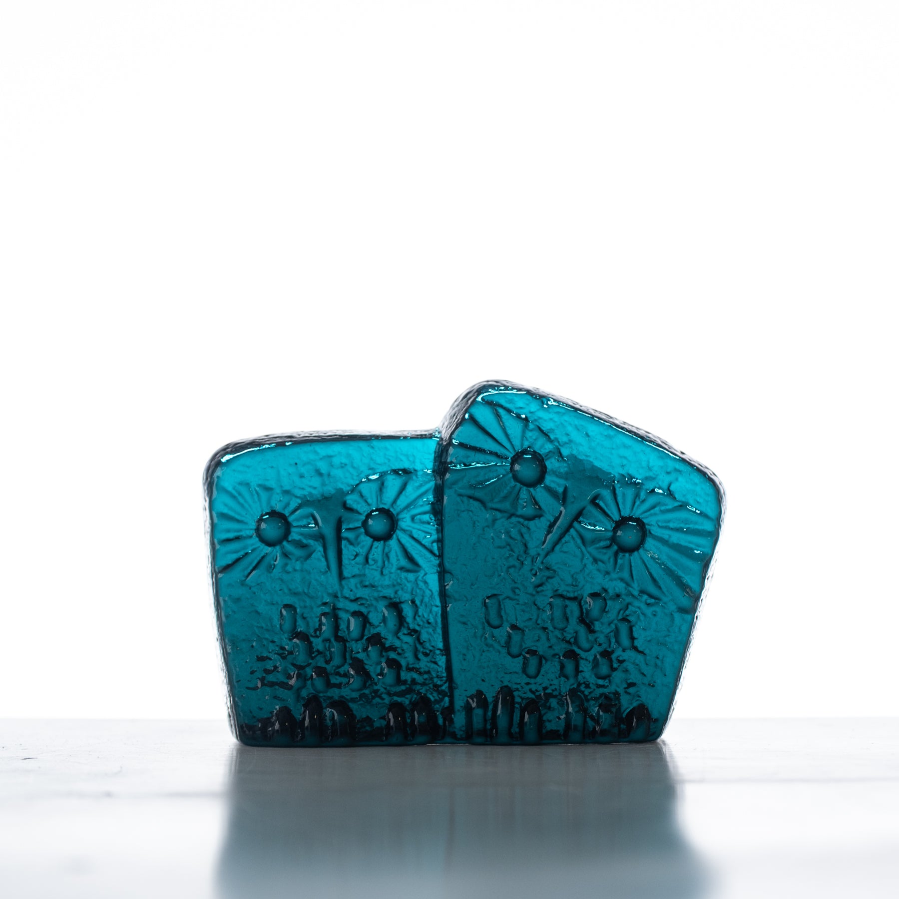 A handcrafted blue glass figurine with a flat back, featuring a patterned design, likely representing an owl.