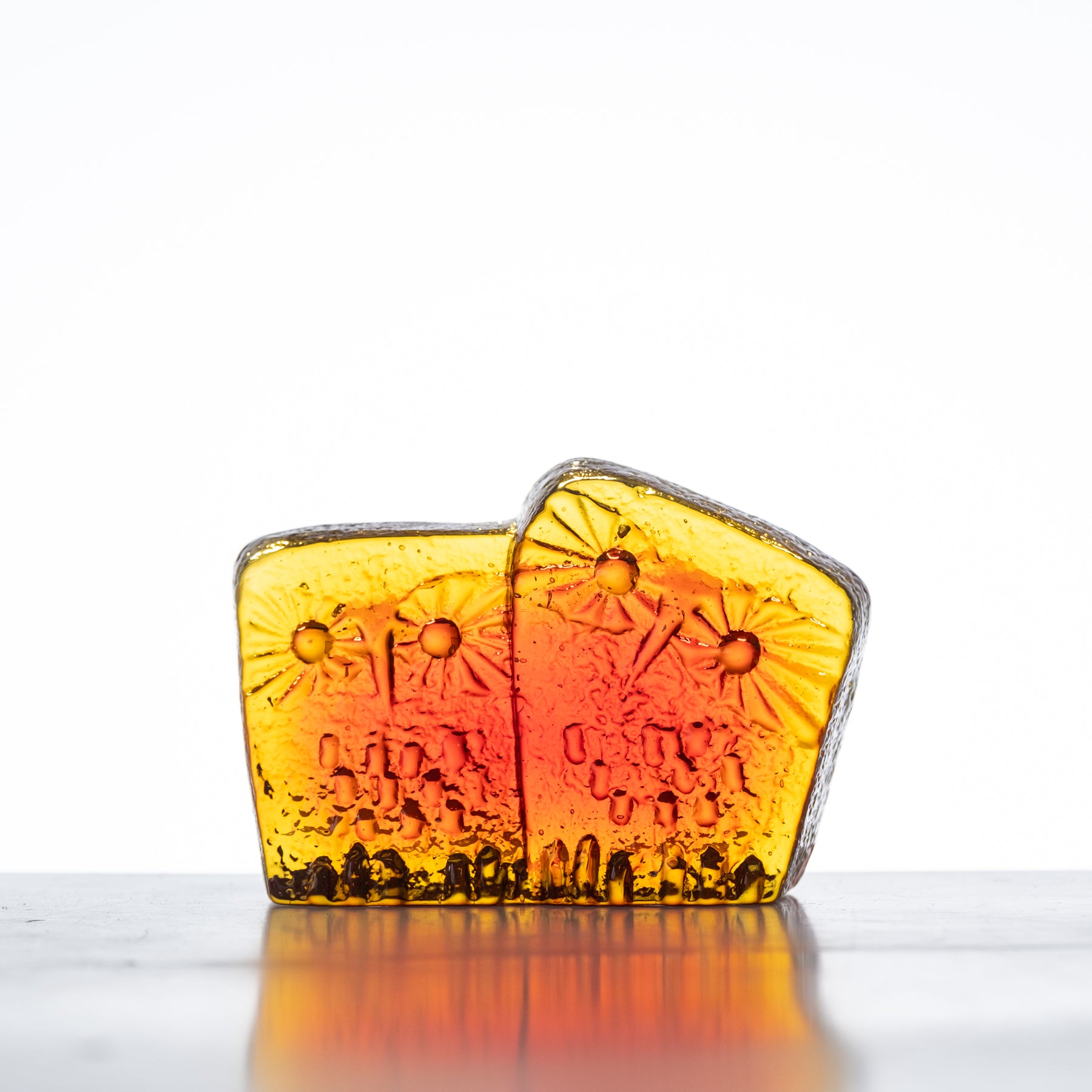 A handcrafted glass figurine with a tangerine color, featuring an owl family design, on a flat surface.