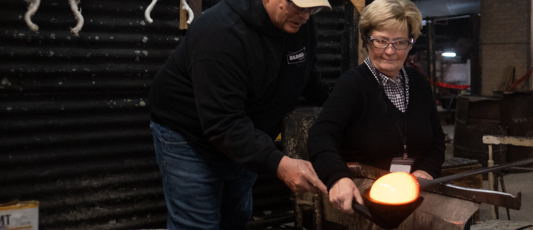 Two people working with glass in a workshop setting