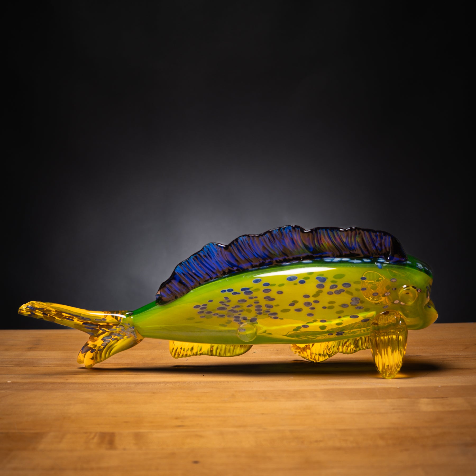 Glass fish sculpture on a wooden surface with a dark background