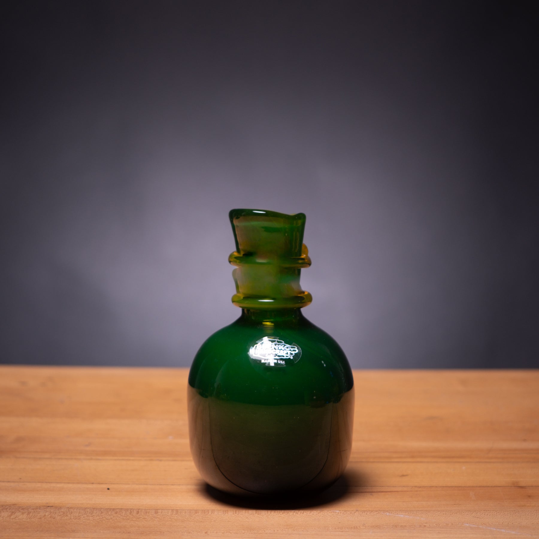 Green glass bottle on a wooden surface with a dark background