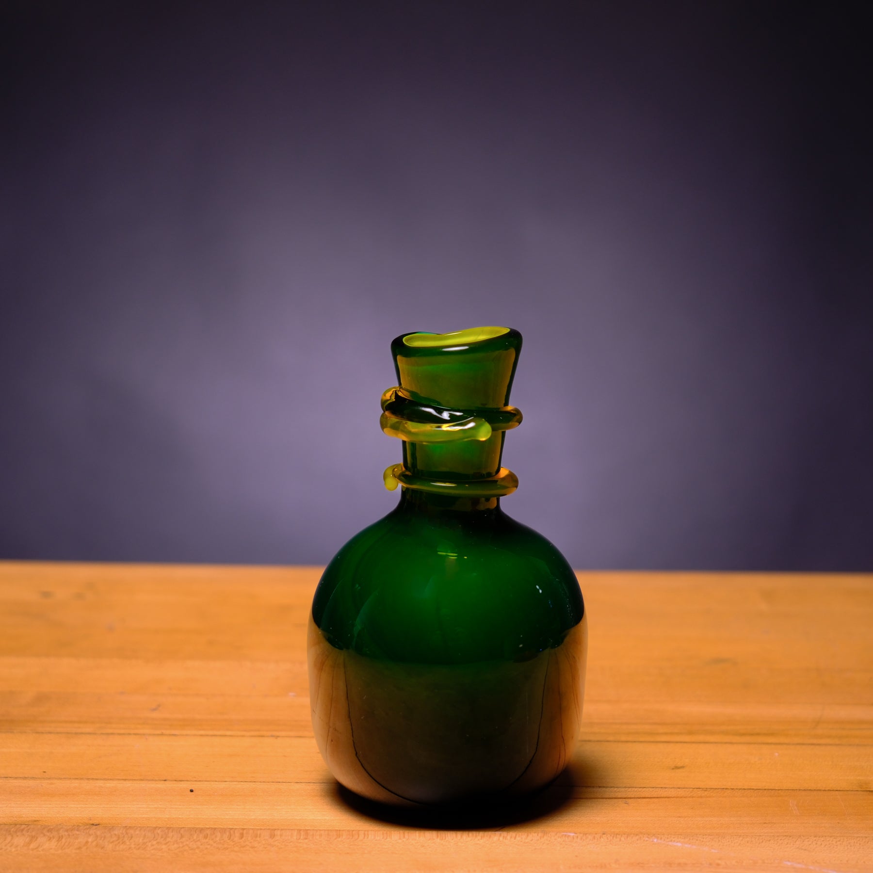Green glass bottle on a wooden surface with a purple background