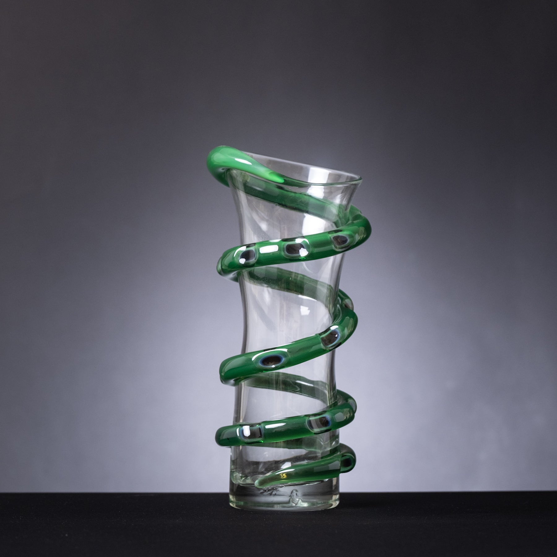 Glass vase with green spiral design on a gray background