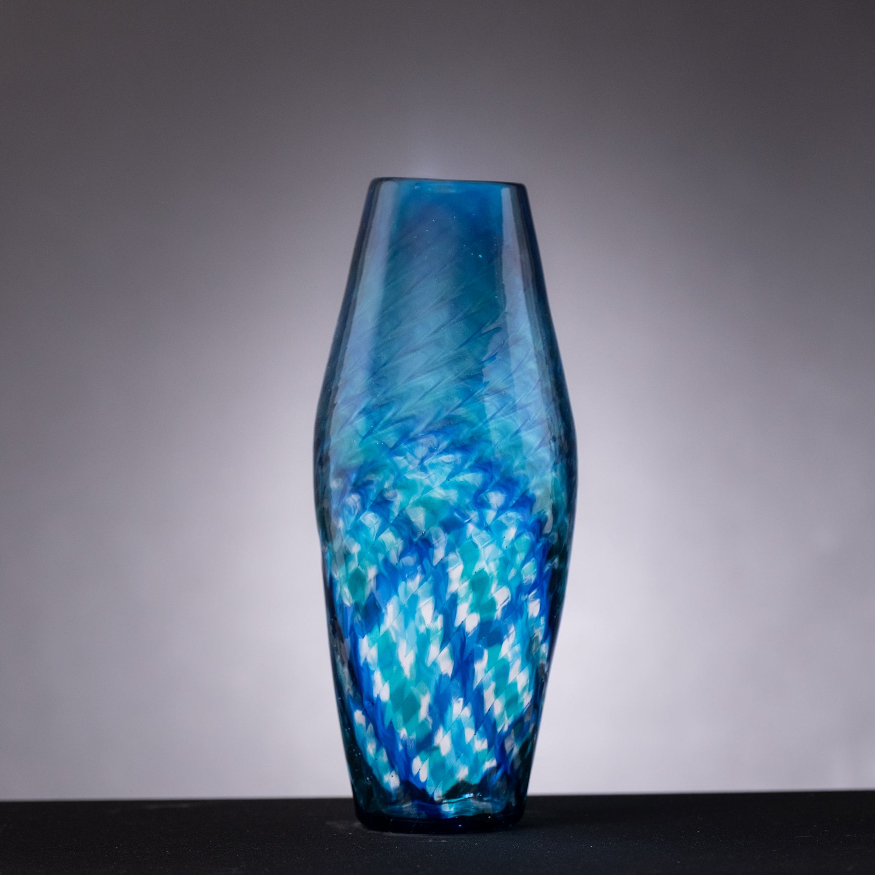 Blue glass vase with a textured pattern on a gray background