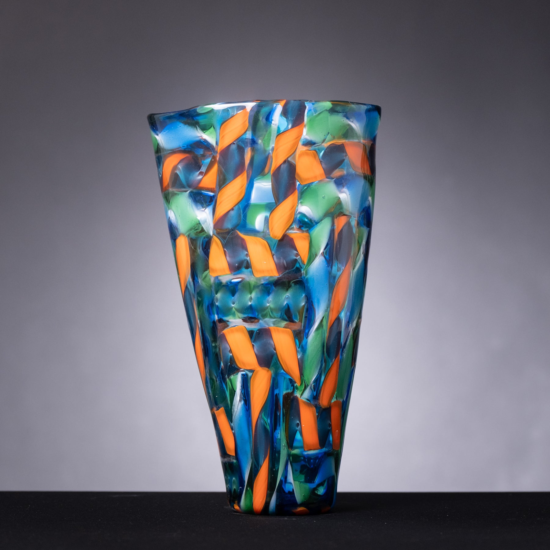 Colorful glass vase with geometric pattern on a gray background