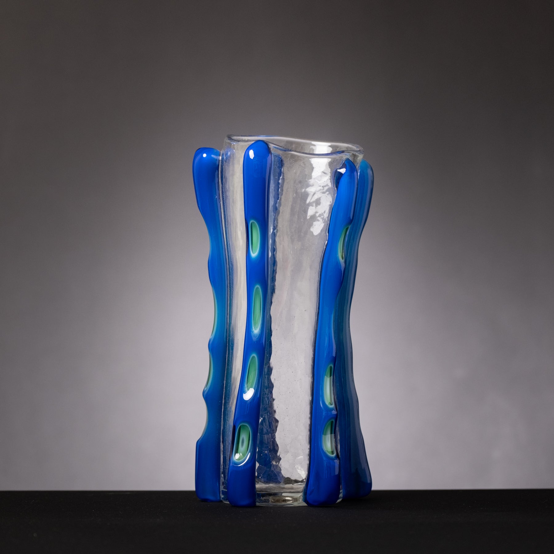 Clear glass vase with blue textured exterior on a gray background