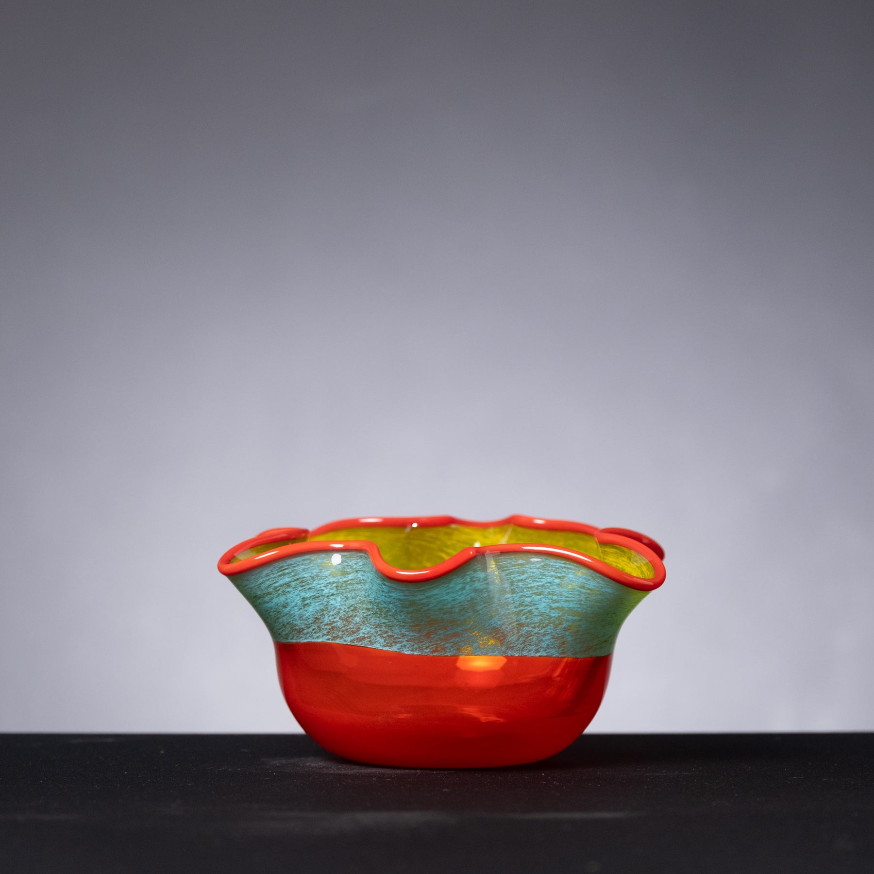 Colorful glass bowl with red and green design on a gray background