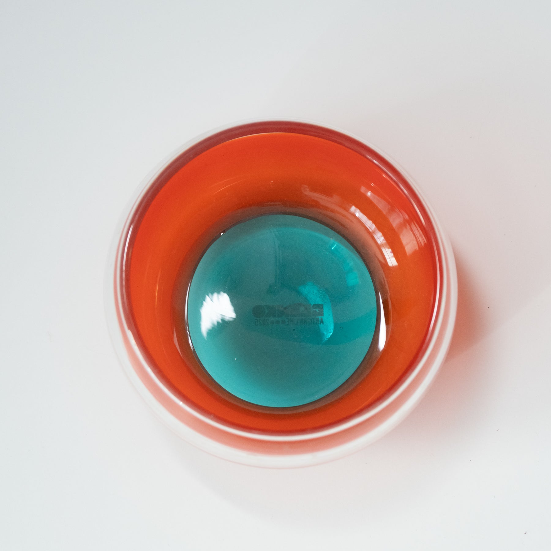 Top view of a red container with a blue liquid on a white background