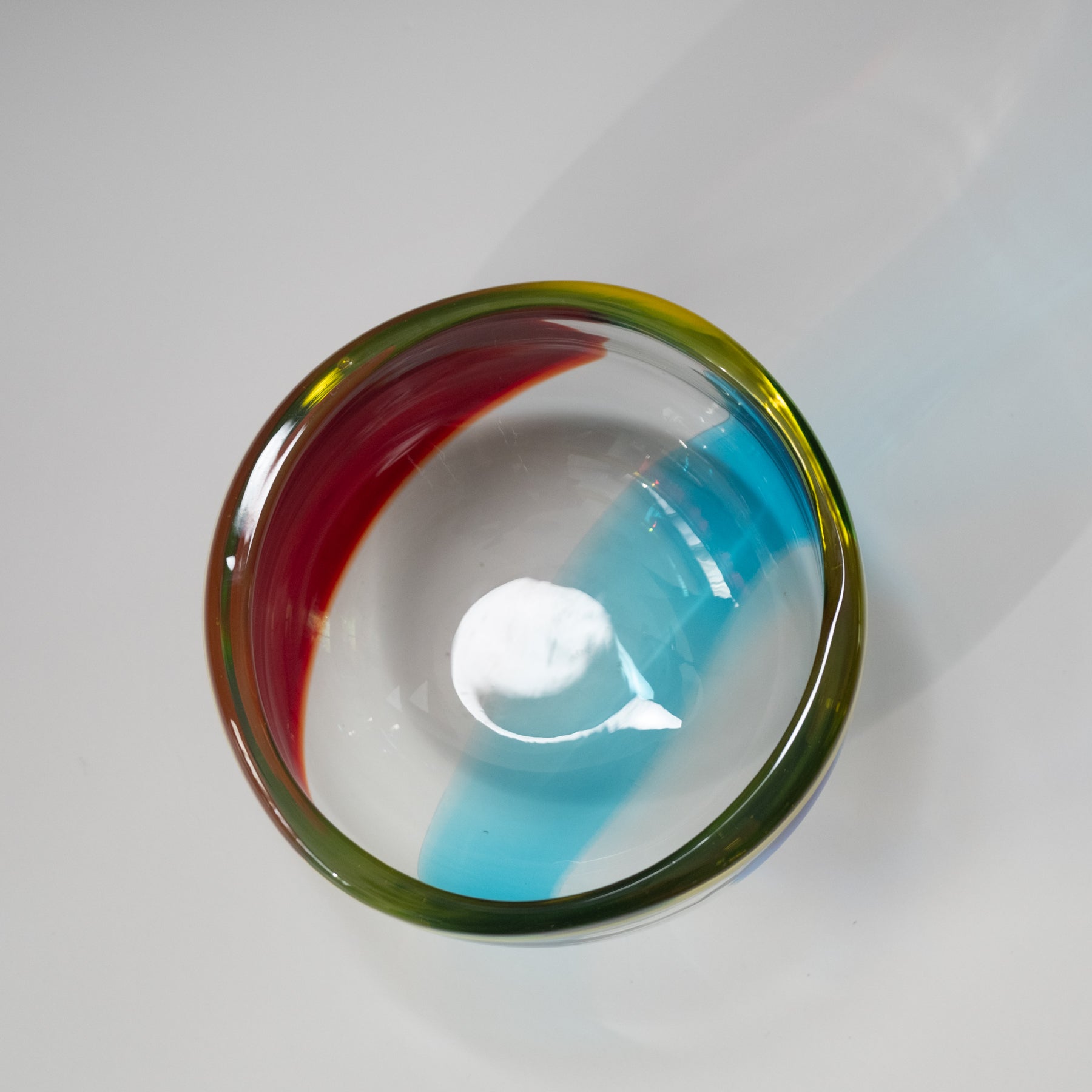 Colorful glass bowl with a white powdery substance on a white background