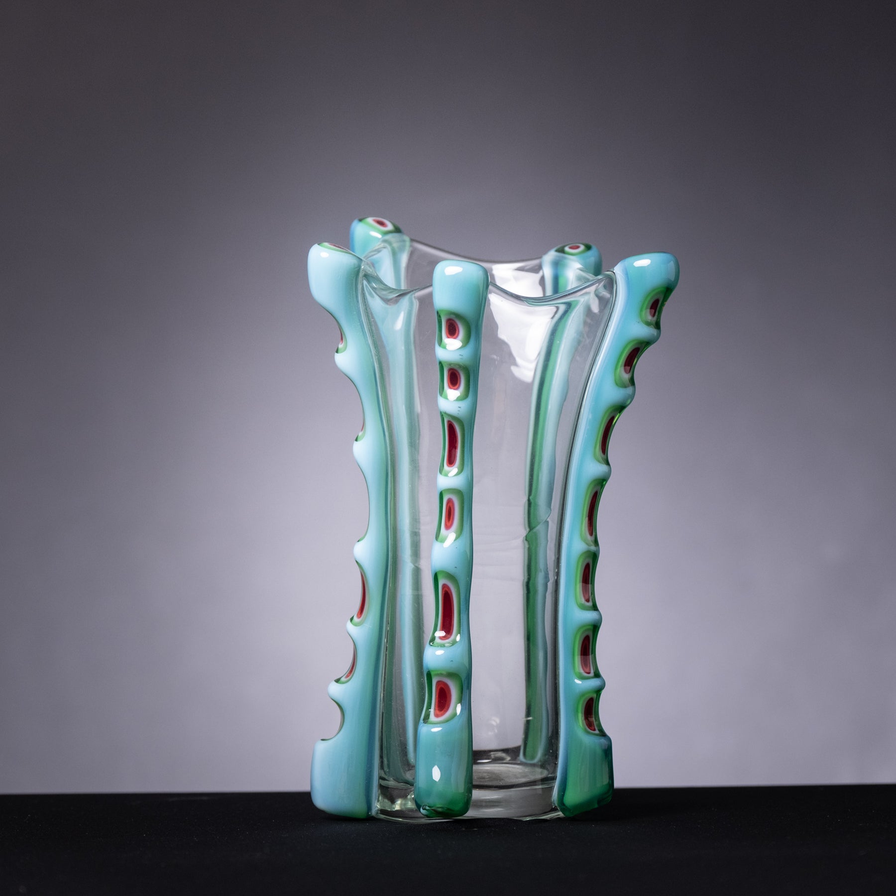 Glass vase with green ribbed exterior and clear center on a dark background