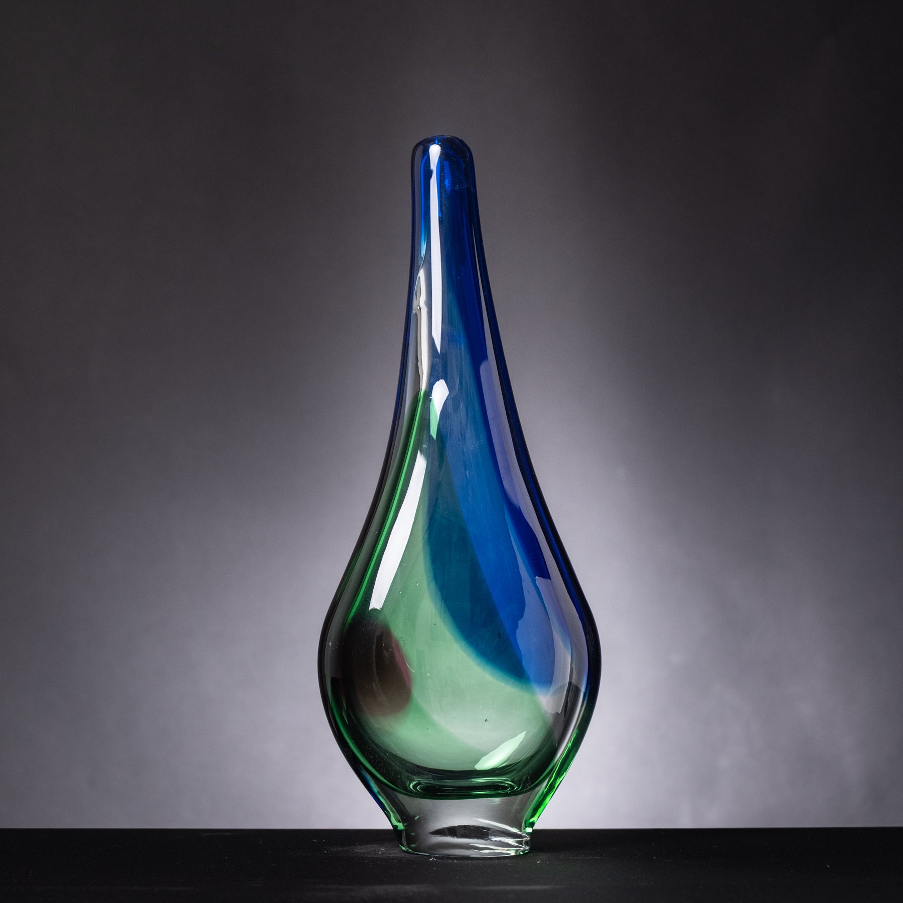 Glass vase with blue and green gradient on a dark background
