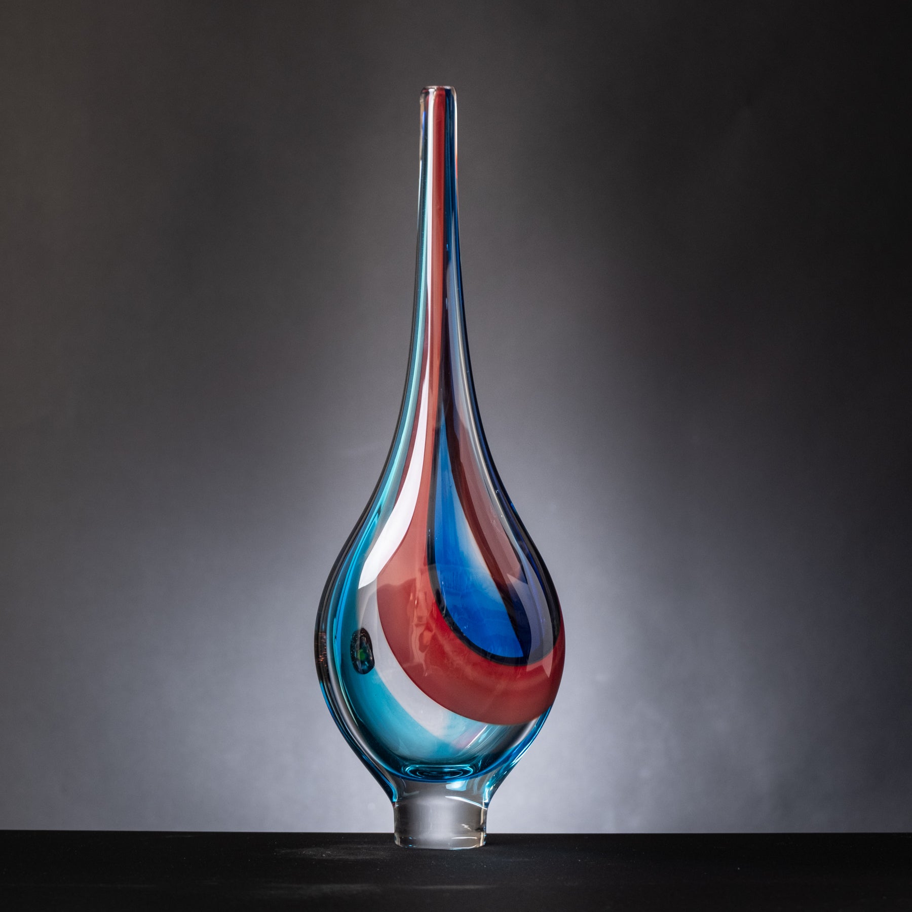 Glass vase with blue and red gradient on a dark background