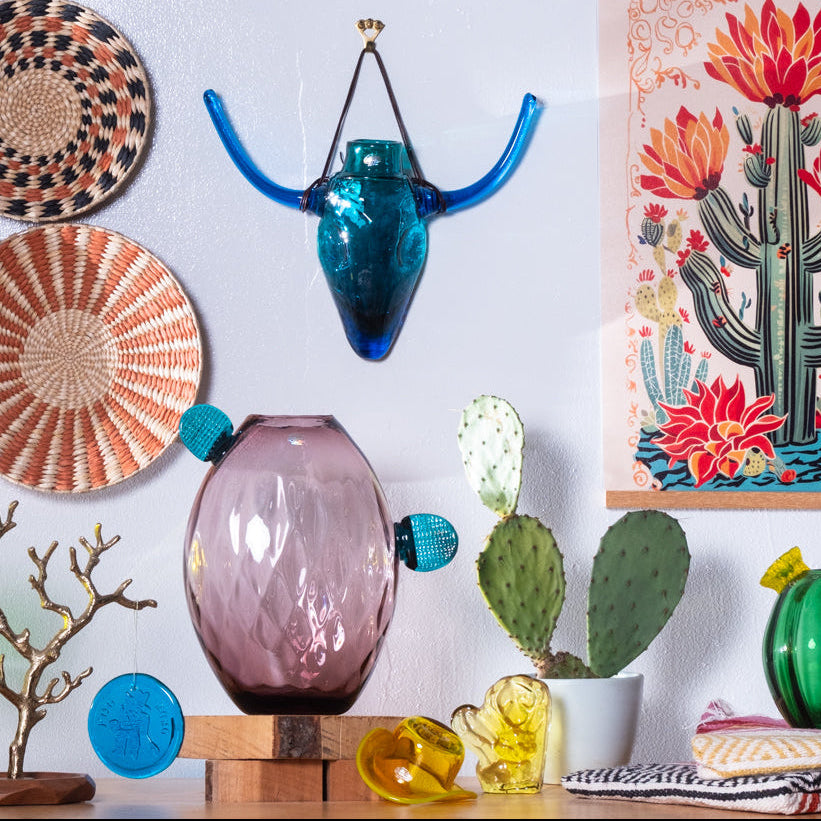 Decorative items including a pink vase, blue wall art, and a cactus painting on a white wall.