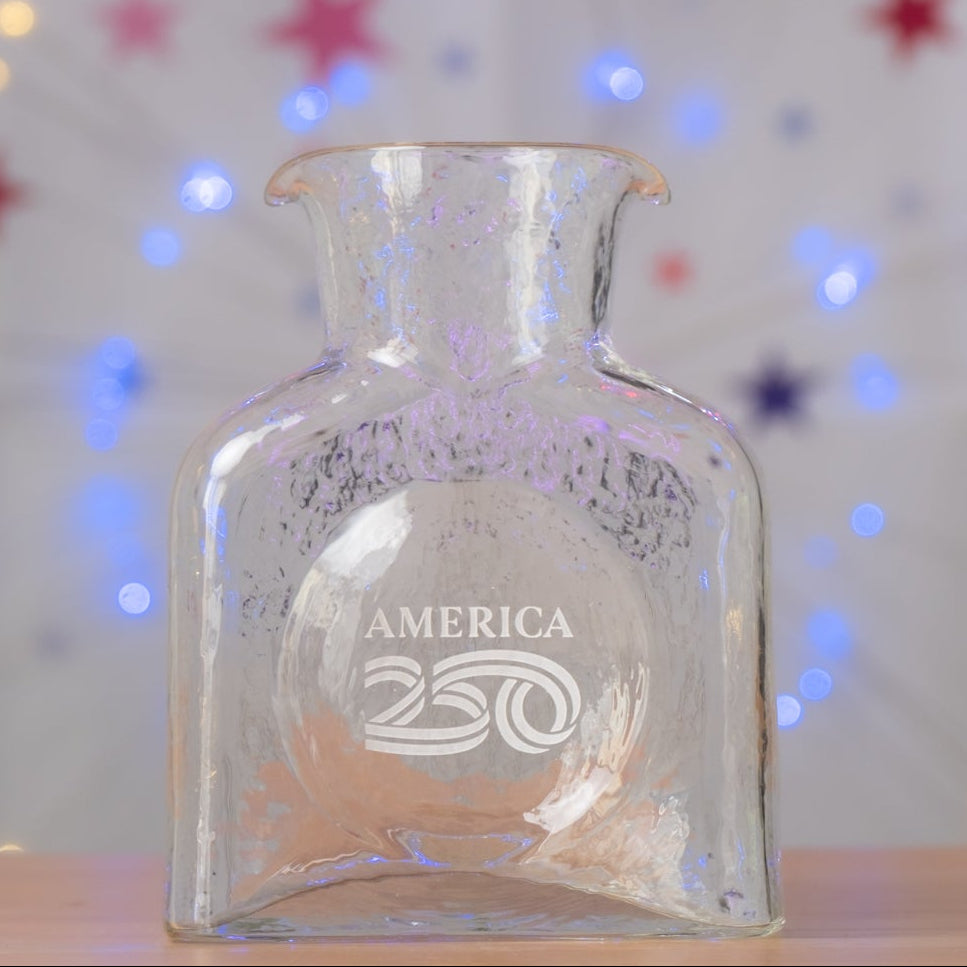 Clear glass bottle with 'America' engraving on a star-patterned background with lights