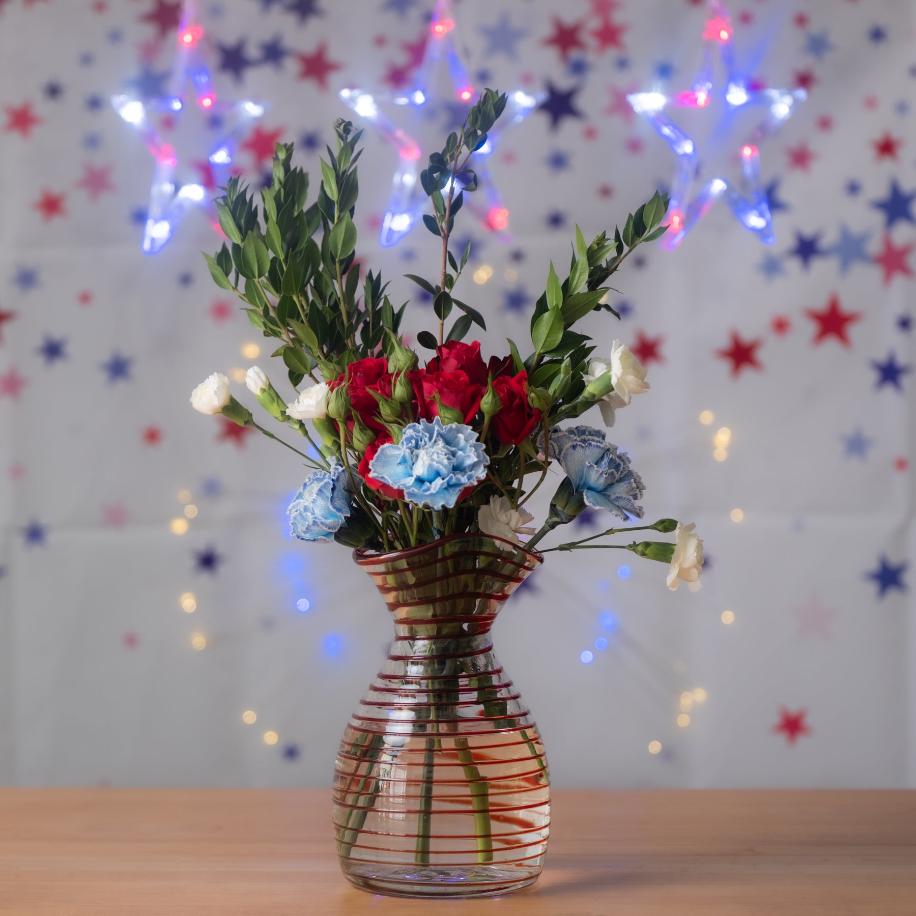 Vase with flowers on a table with a festive background of stars and lights.
