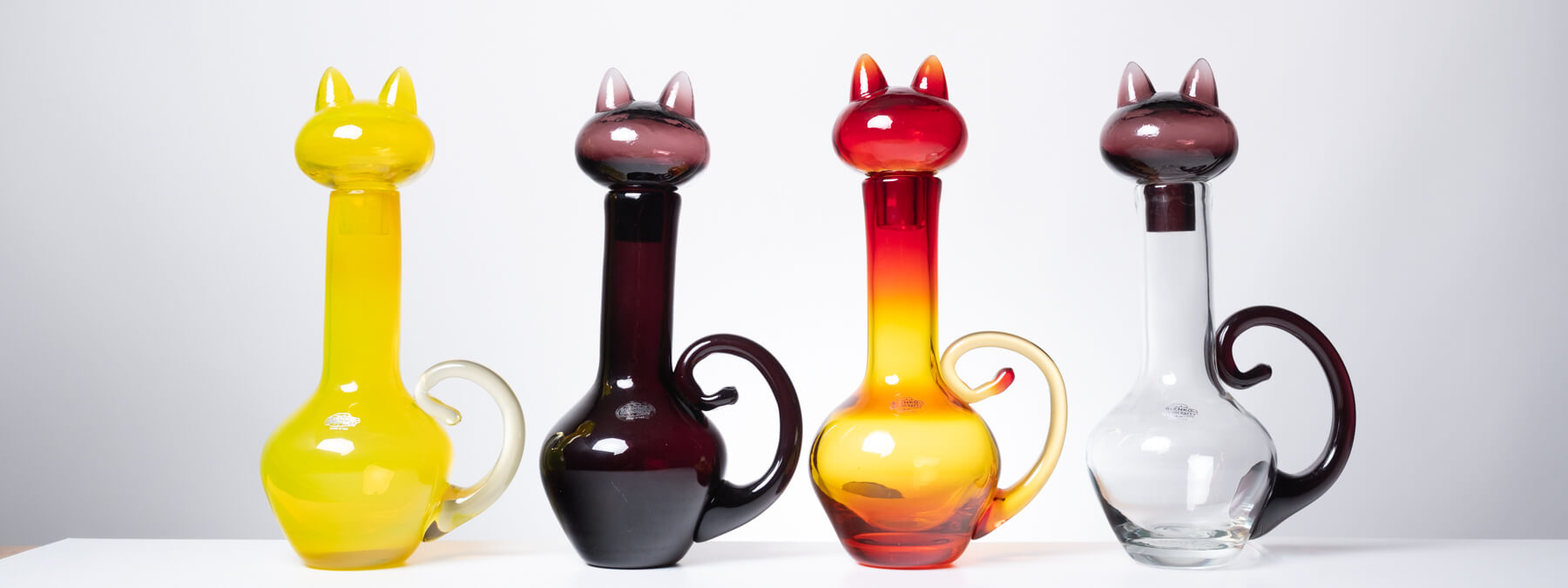 Four colorful cat shaped bottles against a white background