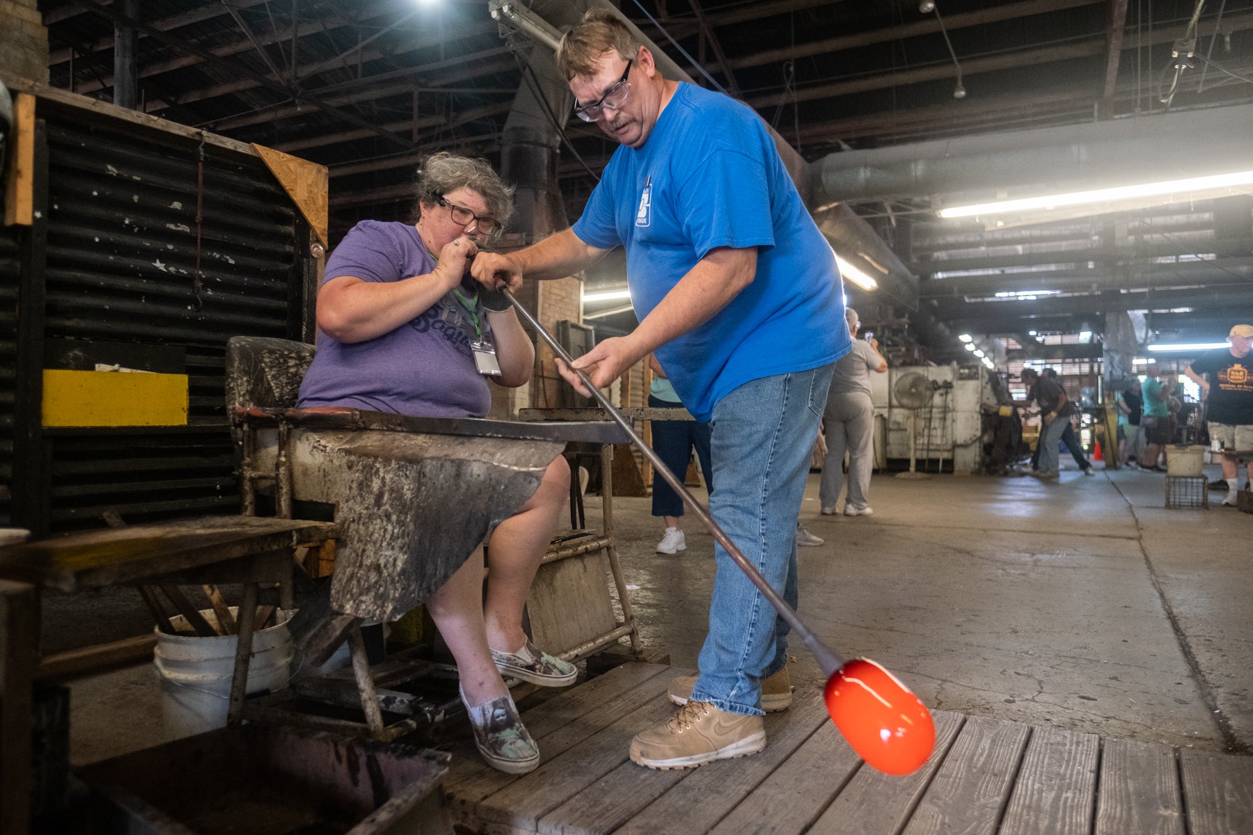 Two people working together in a warehouse setting with equipment and tools.